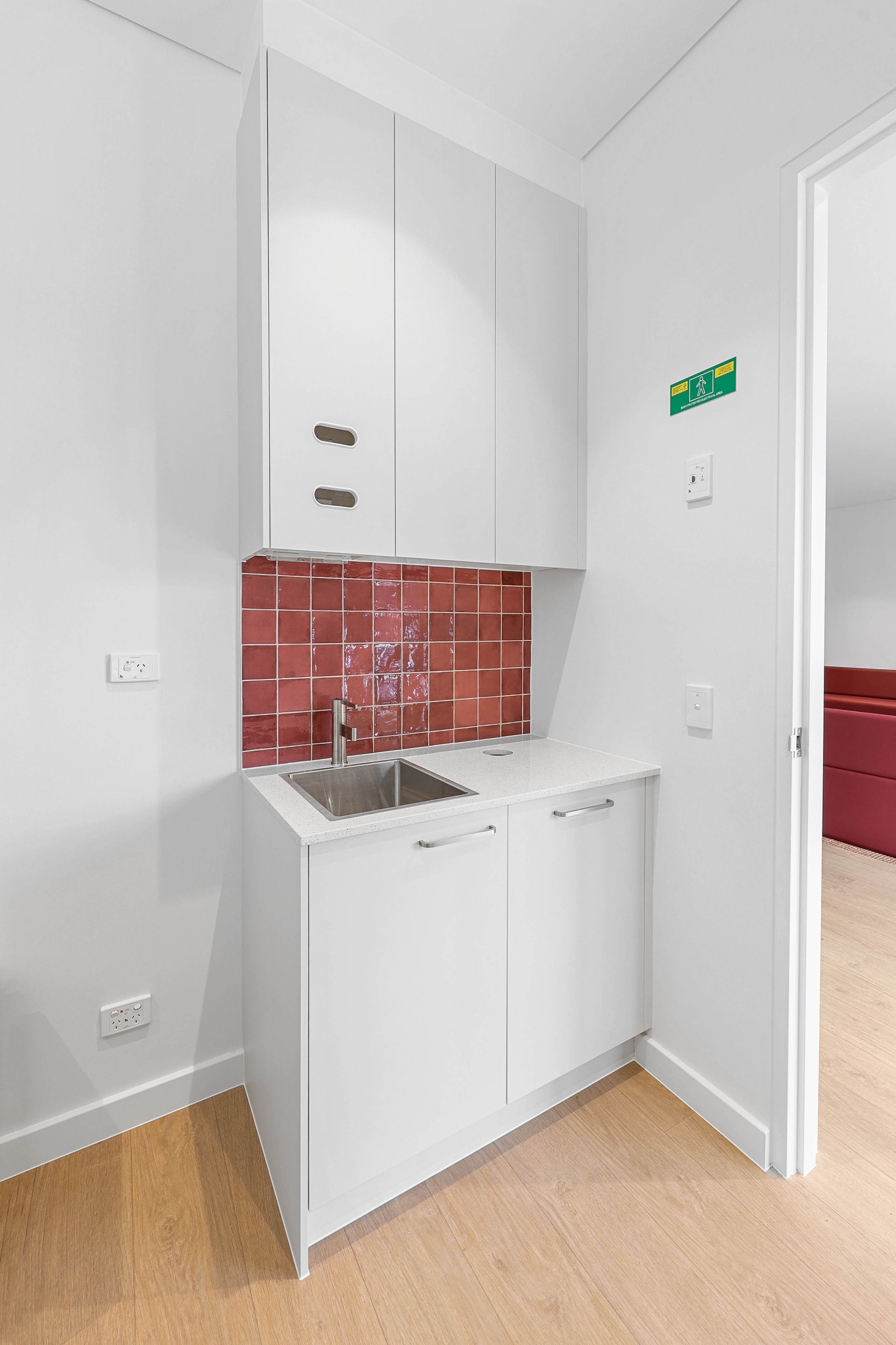 Compact White Kitchenette With Sink, Red Tile Backsplash — Above & Beyond Interiors in Smeaton Grange, NSW