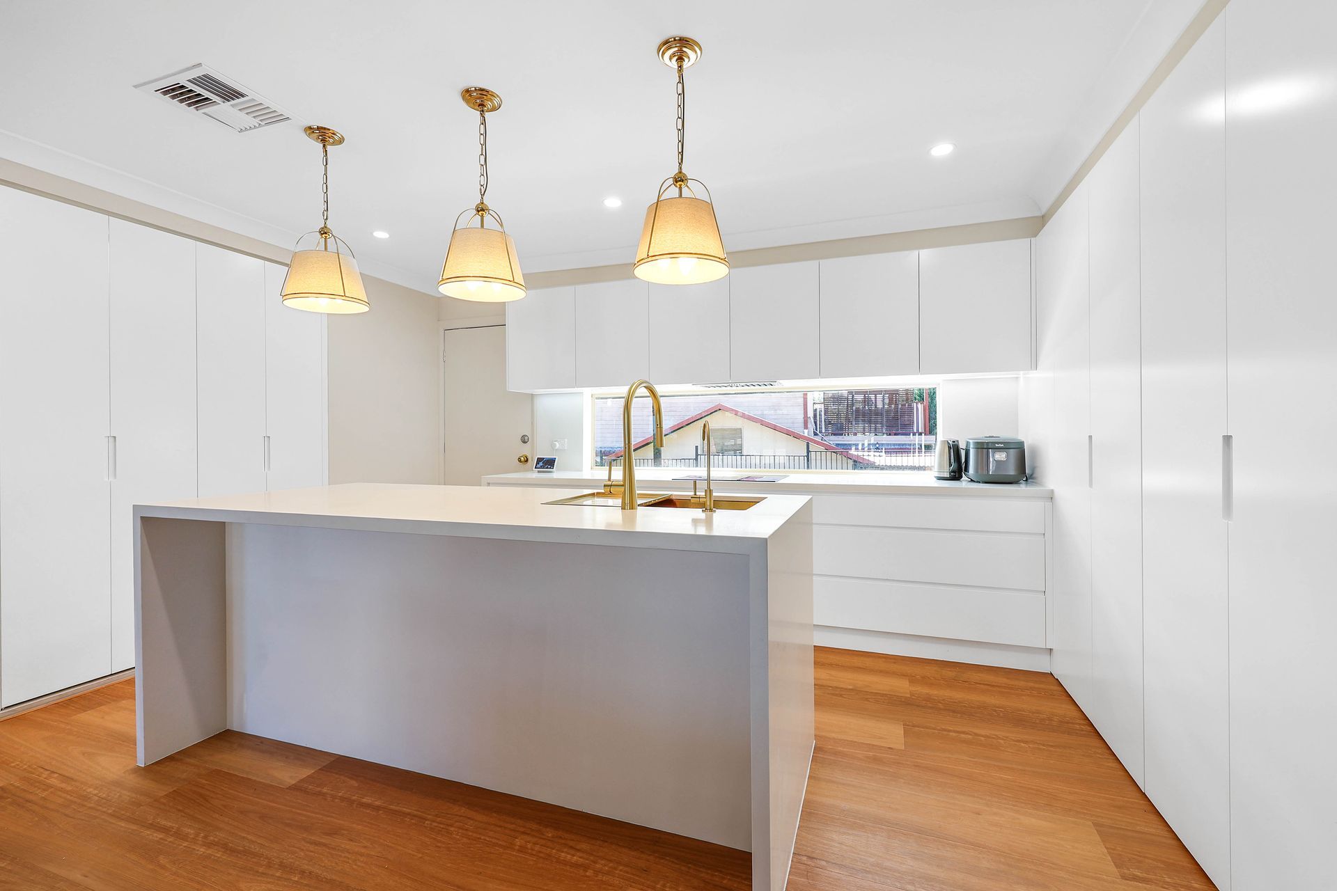 Bright Modern White Kitchen With Wood Floors — Above & Beyond Interiors in Smeaton Grange, NSW