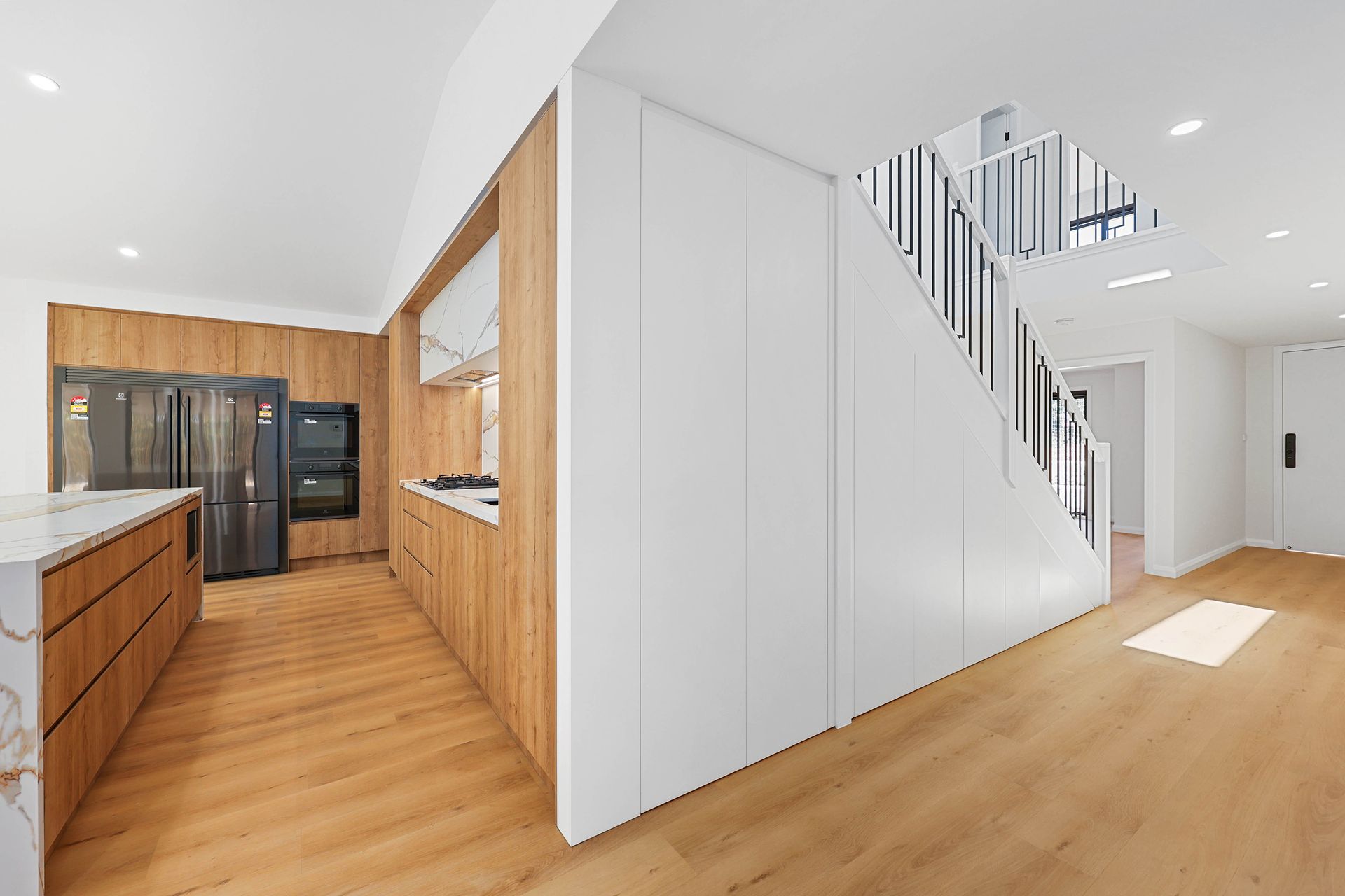 Bright Modern Kitchen and Hallway with Wood Floors — Above & Beyond Interiors in Smeaton Grange, NSW