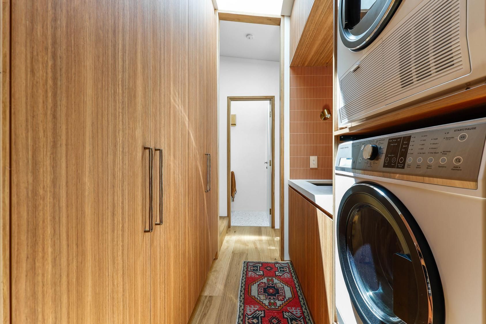 Narrow Laundry Hallway With Wood Cabinets — Above & Beyond Interiors in Smeaton Grange, NSW