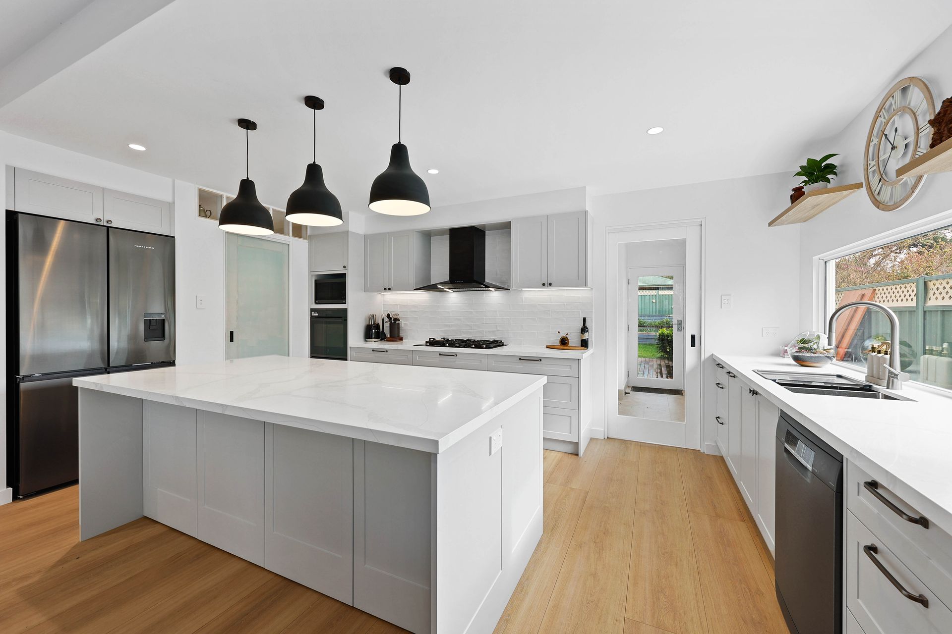 Modern White Kitchen with Black Pendant Lights, Stainless Steel and Appliances — Above & Beyond Interiors in Smeaton Grange, NSW