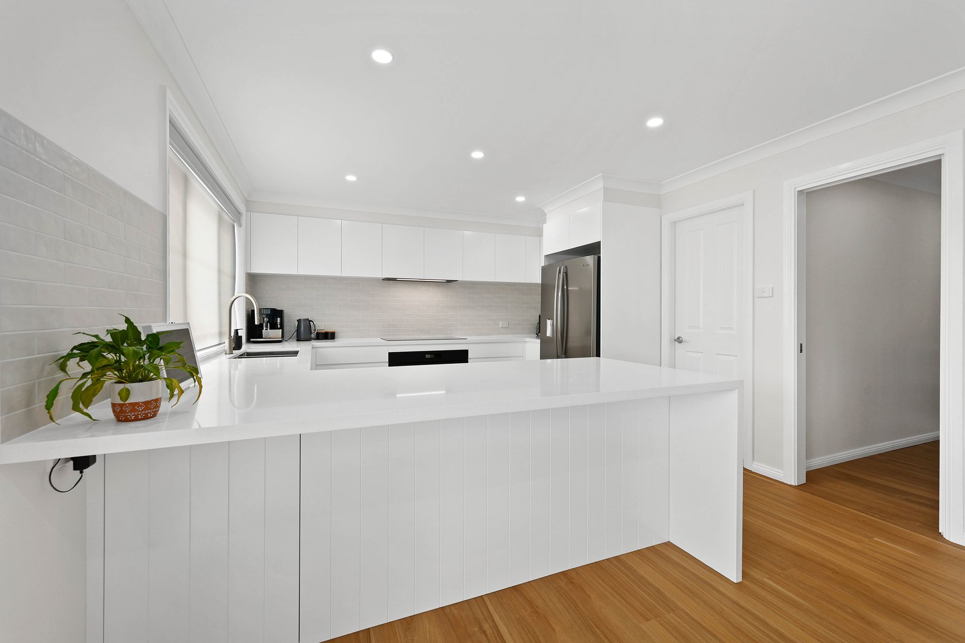 Bright White Modern Kitchen with Island, Stainless Steel Fridge — Above & Beyond Interiors in Smeaton Grange, NSW