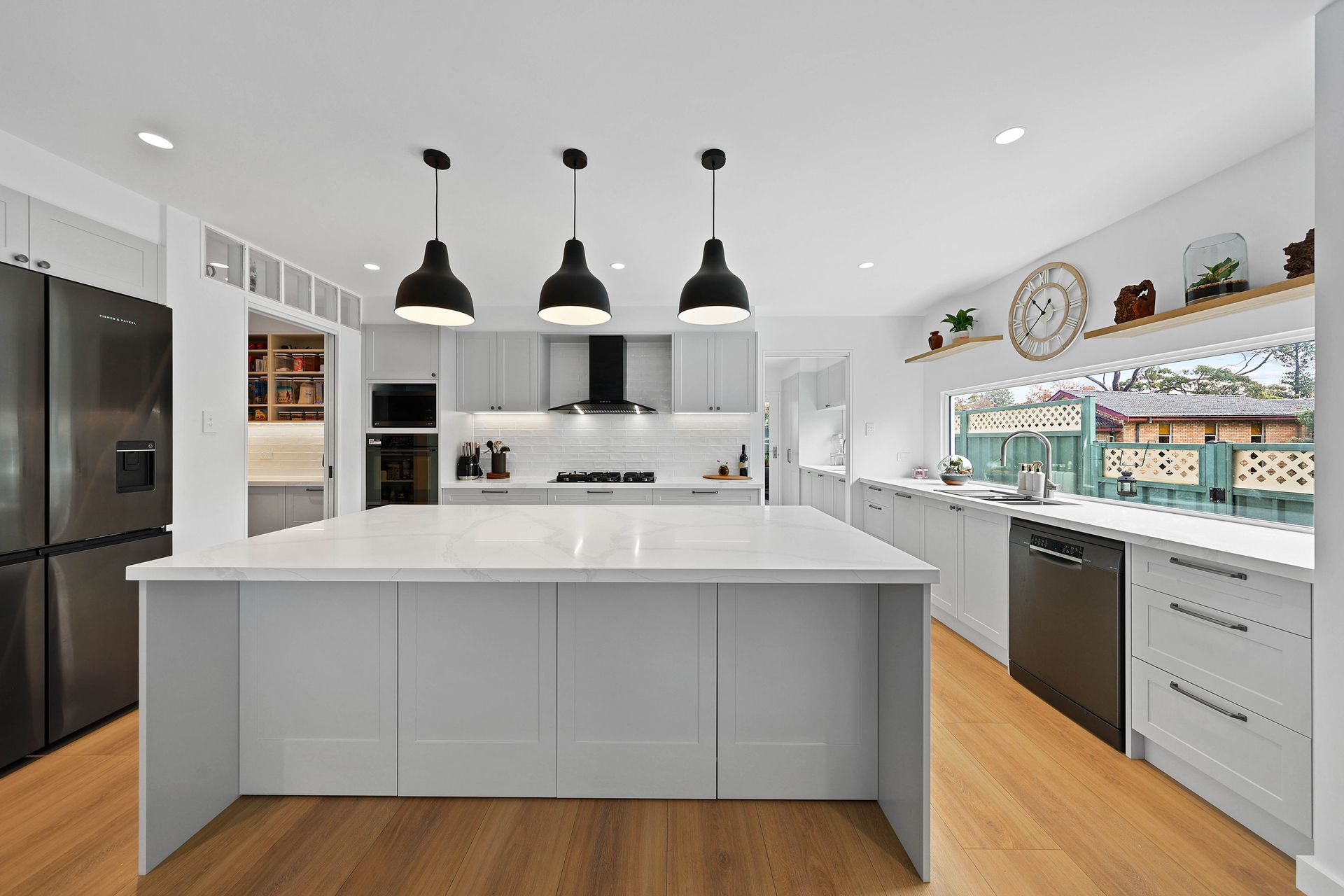 Bright Modern Kitchen with White Island, Black Pendant Lights, and Stainless Appliances — Above & Beyond Interiors in Smeaton Grange, NSW