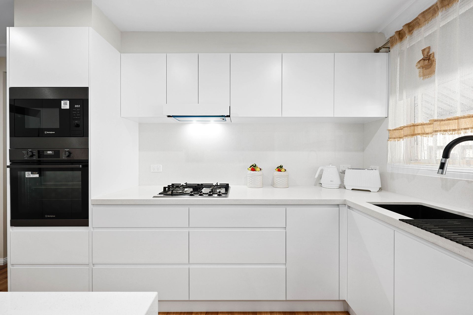 Modern White Kitchen with Sleek Cabinets — Above & Beyond Interiors in Smeaton Grange, NSW