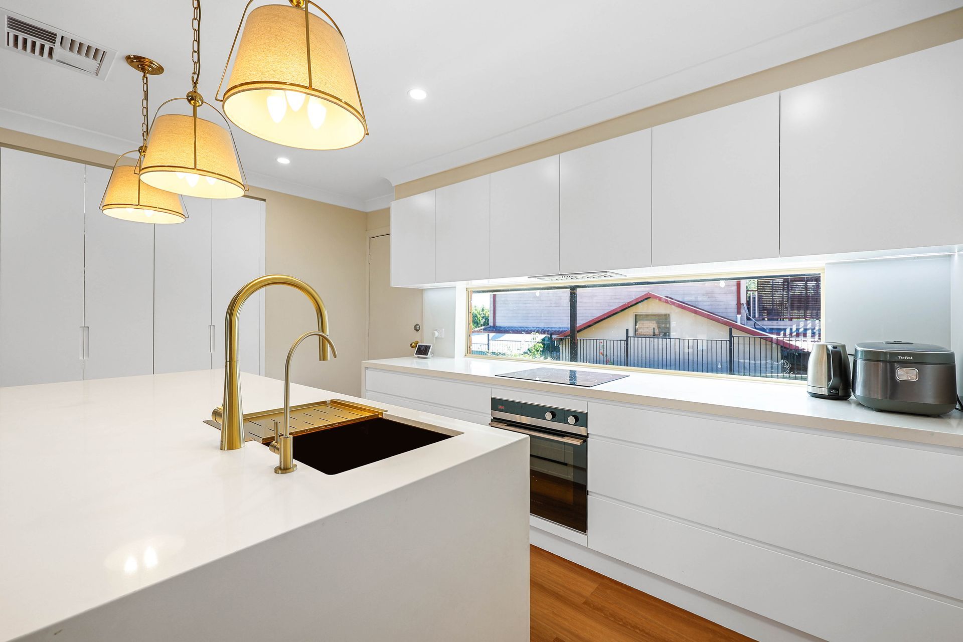 Modern White Kitchen With Gold Pendant Lights — Above & Beyond Interiors in Smeaton Grange, NSW