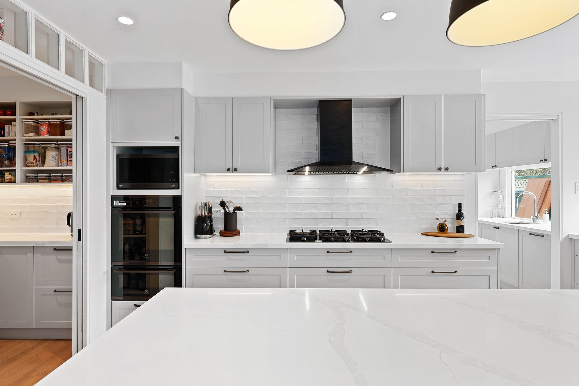 A Kitchen with Gray Cabinets, Black Appliances, and Large Island Countertop — Above & Beyond Interiors in Smeaton Grange, NSW