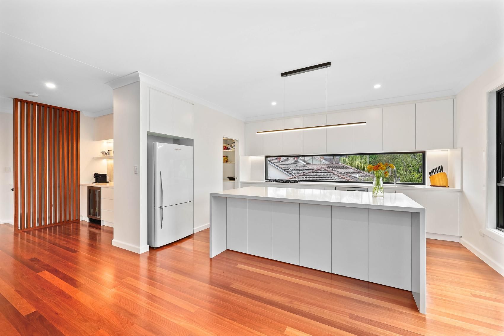 Bright Modern Kitchen with Cabinets, Gray Island, and Warm Wood Floors — Above & Beyond Interiors in Smeaton Grange, NSW