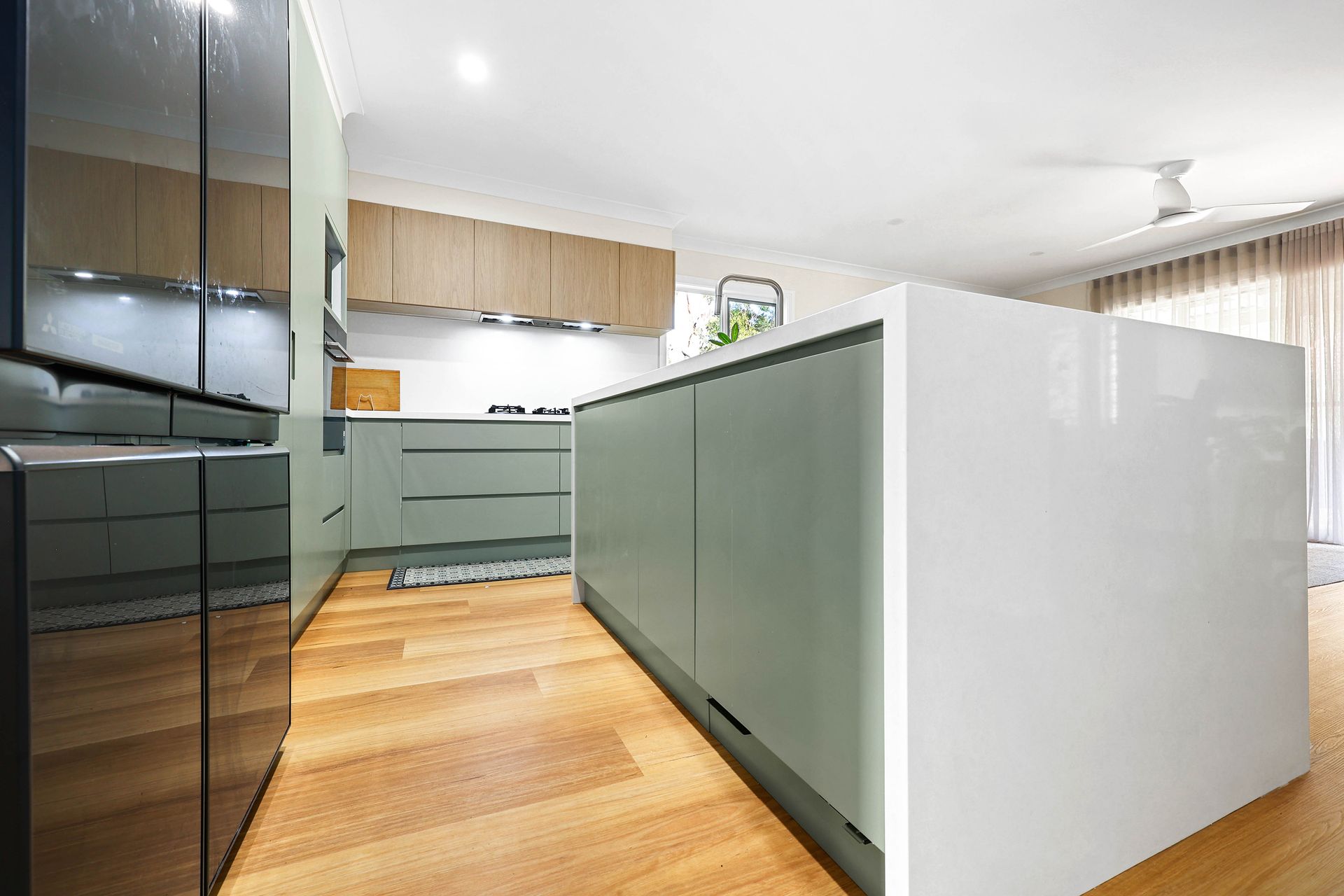 A Kitchen with White Island, Light Wood Cabinets, and Black Stainless Appliances — Above & Beyond Interiors in Smeaton Grange, NSW