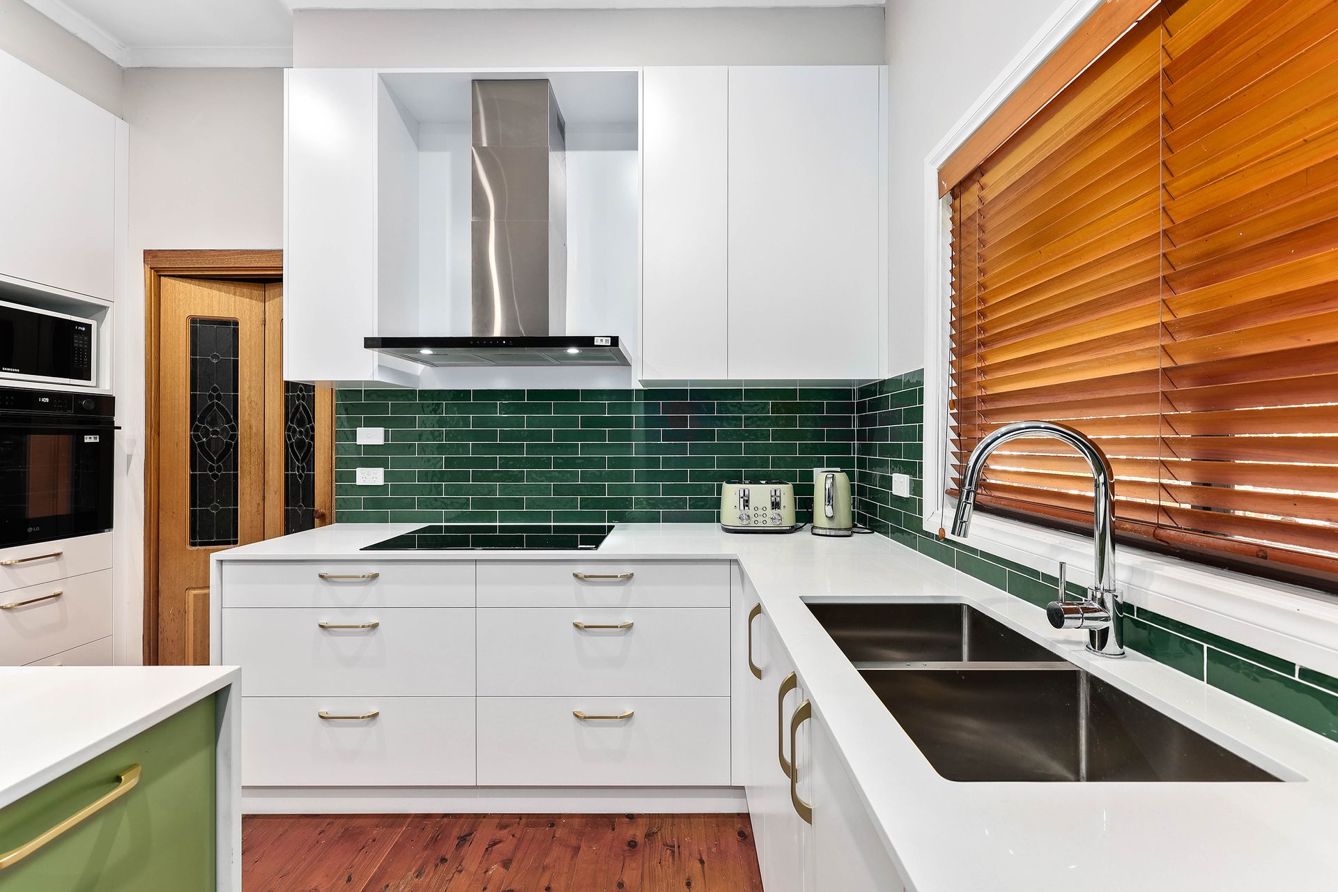 A White Kitchen with Green Tile Backsplash — Above & Beyond Interiors in Smeaton Grange, NSW
