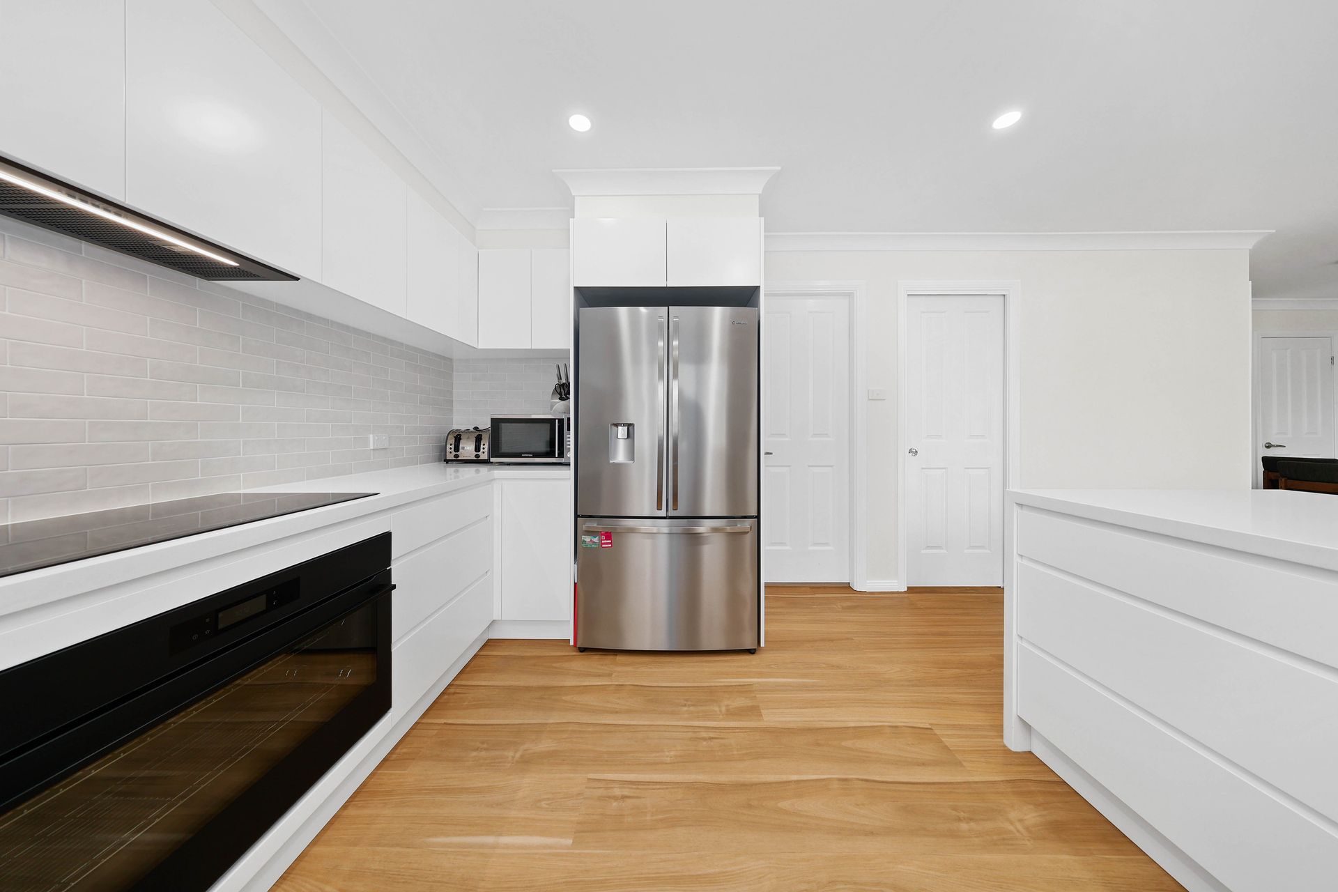 A Kitchen with Stainless Steel Refrigerator and Wood Floor — Above & Beyond Interiors in Smeaton Grange, NSW
