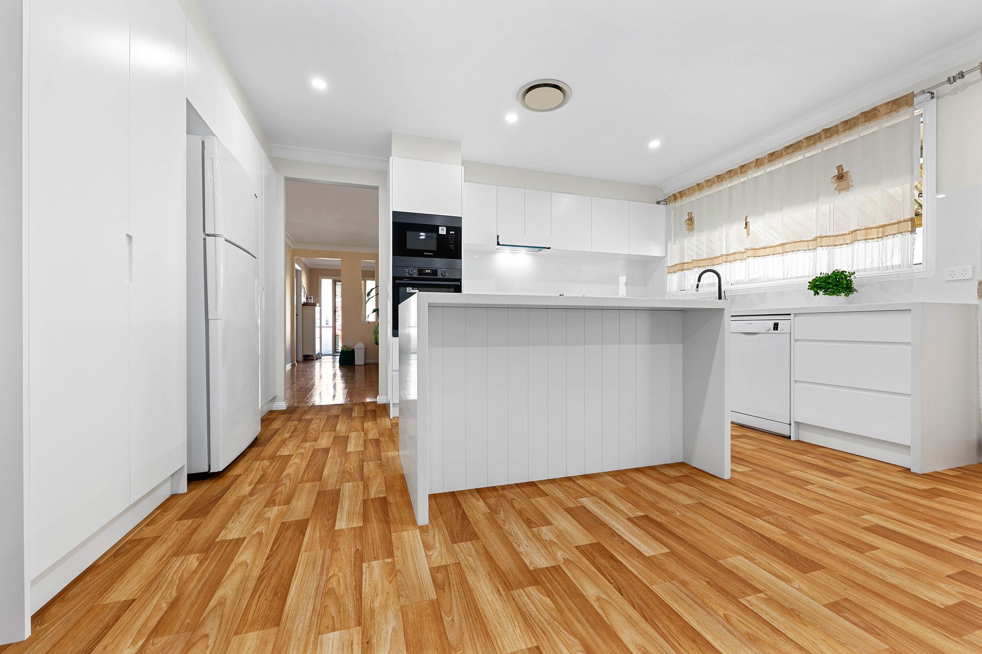 Bright White Modern Kitchen with Wood Floors — Above & Beyond Interiors in Smeaton Grange, NSW