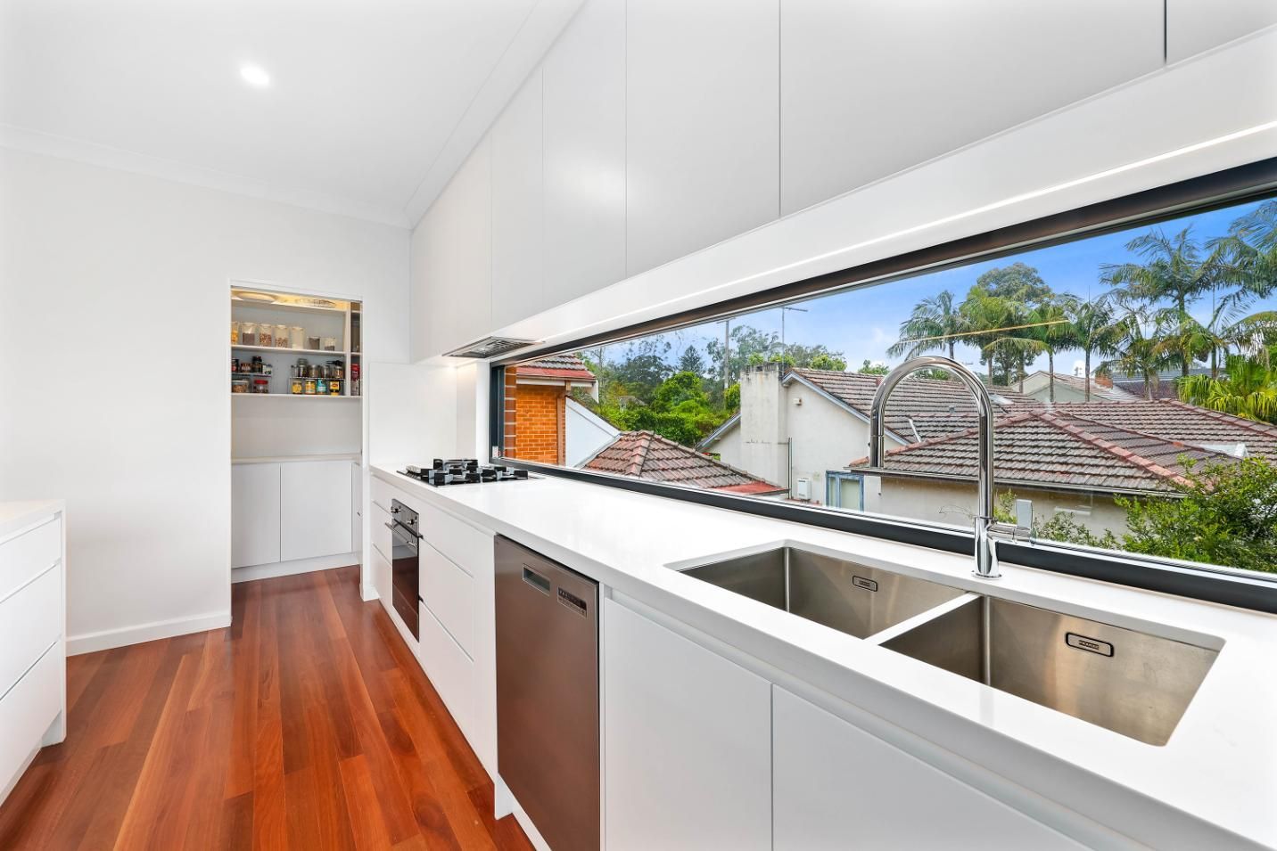 Bright Modern Kitchen with White Cabinets, Long Window, and Polished Wooden Floor — Above & Beyond Interiors in Smeaton Grange, NSW