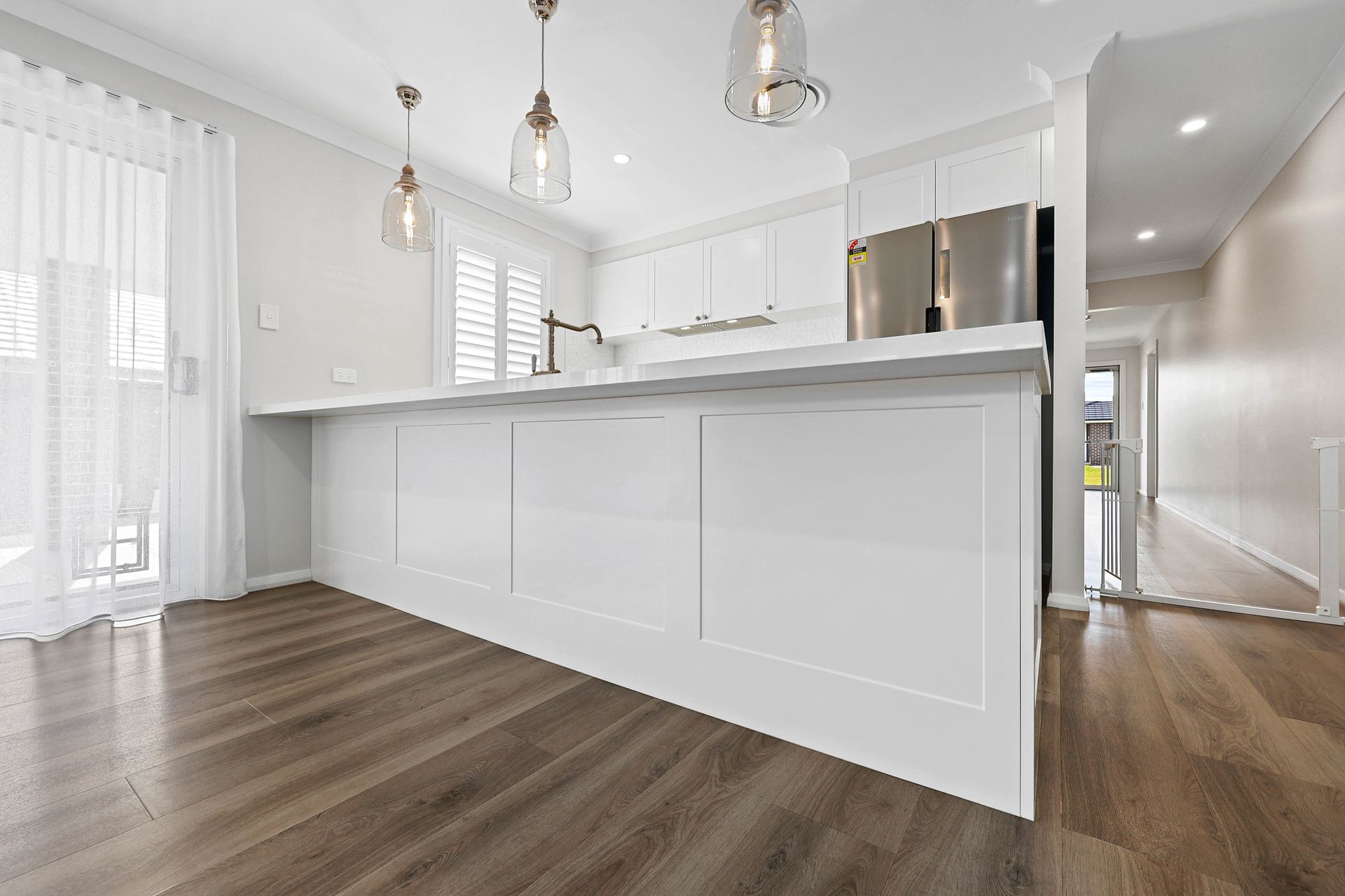 A Kitchen with Large Island, Pendant Lights, and Wood Floor — Above & Beyond Interiors in Smeaton Grange, NSW