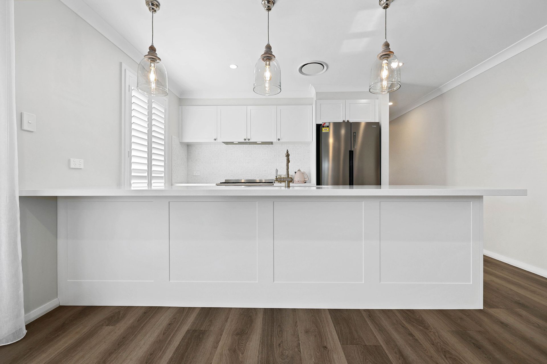 A Kitchen with Dark Wood Floor, and Stainless Steel Fridge — Above & Beyond Interiors in Smeaton Grange, NSW