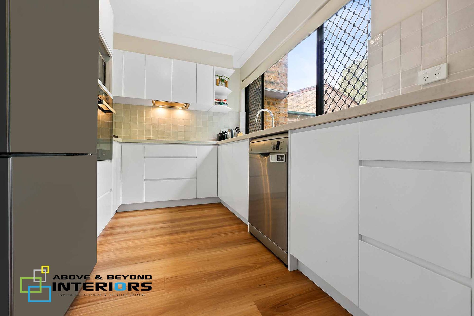 Modern White Kitchen with Wood Flooring — Above & Beyond Interiors in Smeaton Grange, NSW