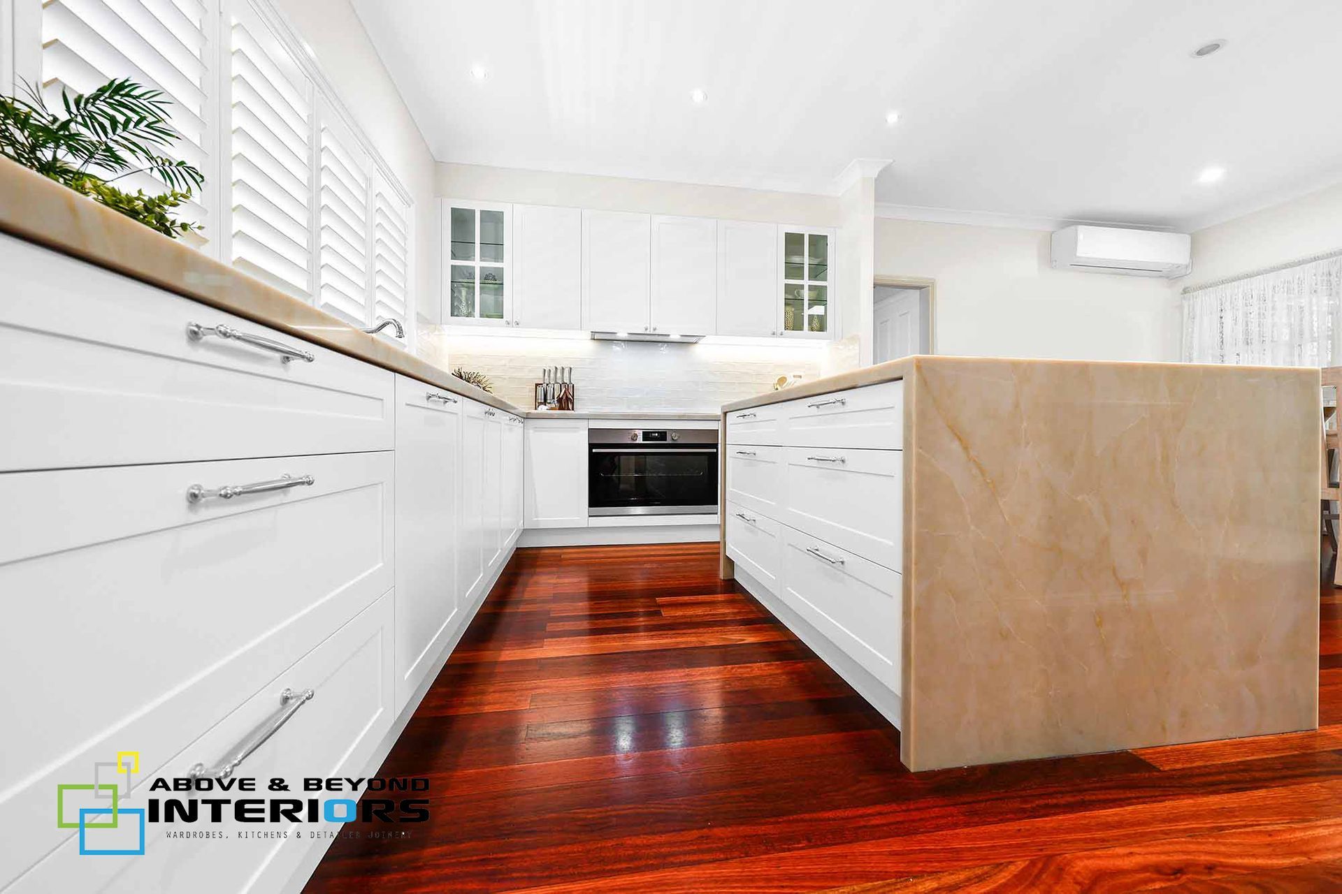 Bright Modern Kitchen with White Cabinets, Wood Island, and Dark Hardwood Floors — Above & Beyond Interiors in Smeaton Grange, NSW