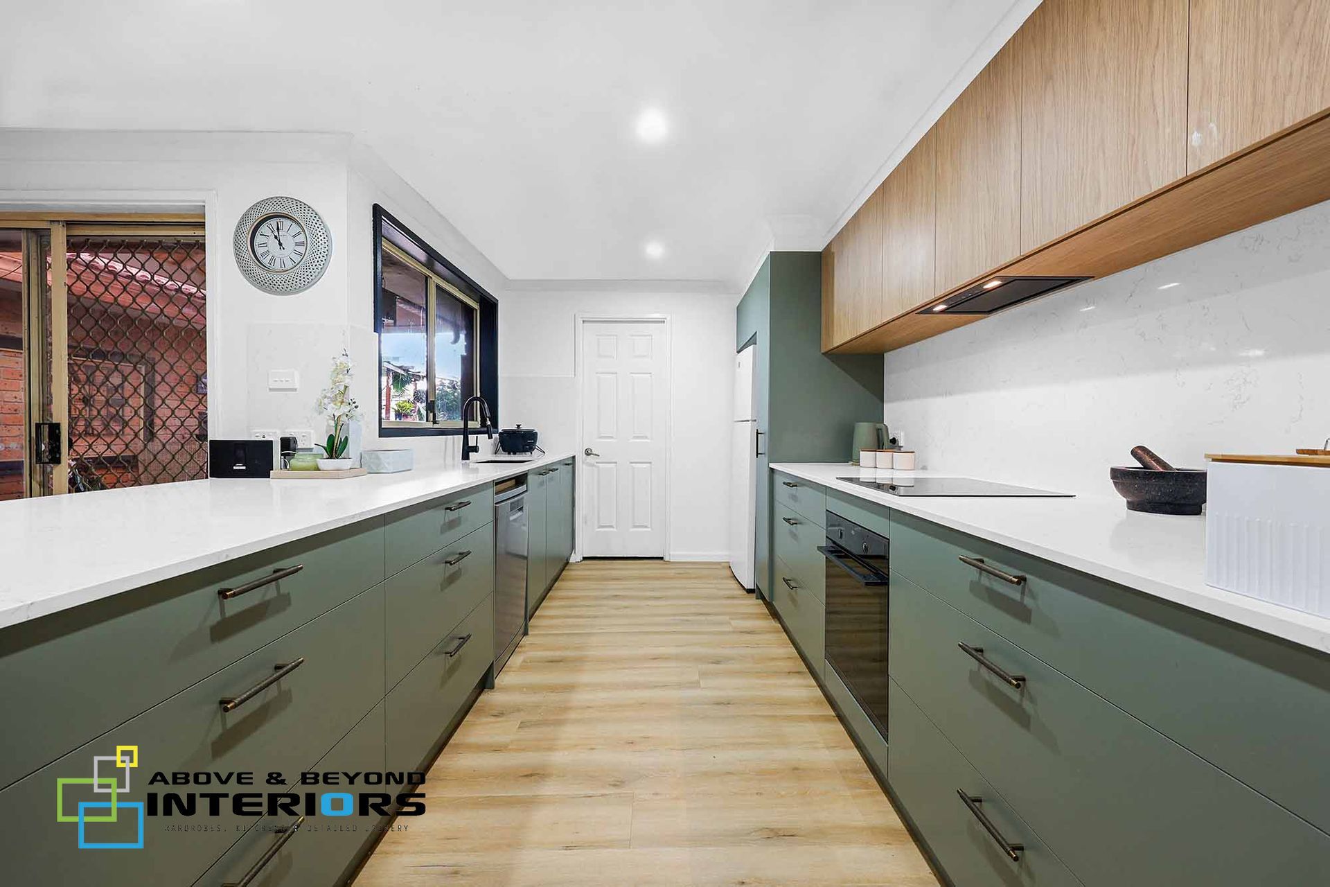 A Kitchen with Green Lower Cabinets, White Countertops, and Light Wood Flooring — Above & Beyond Interiors in Smeaton Grange, NSW