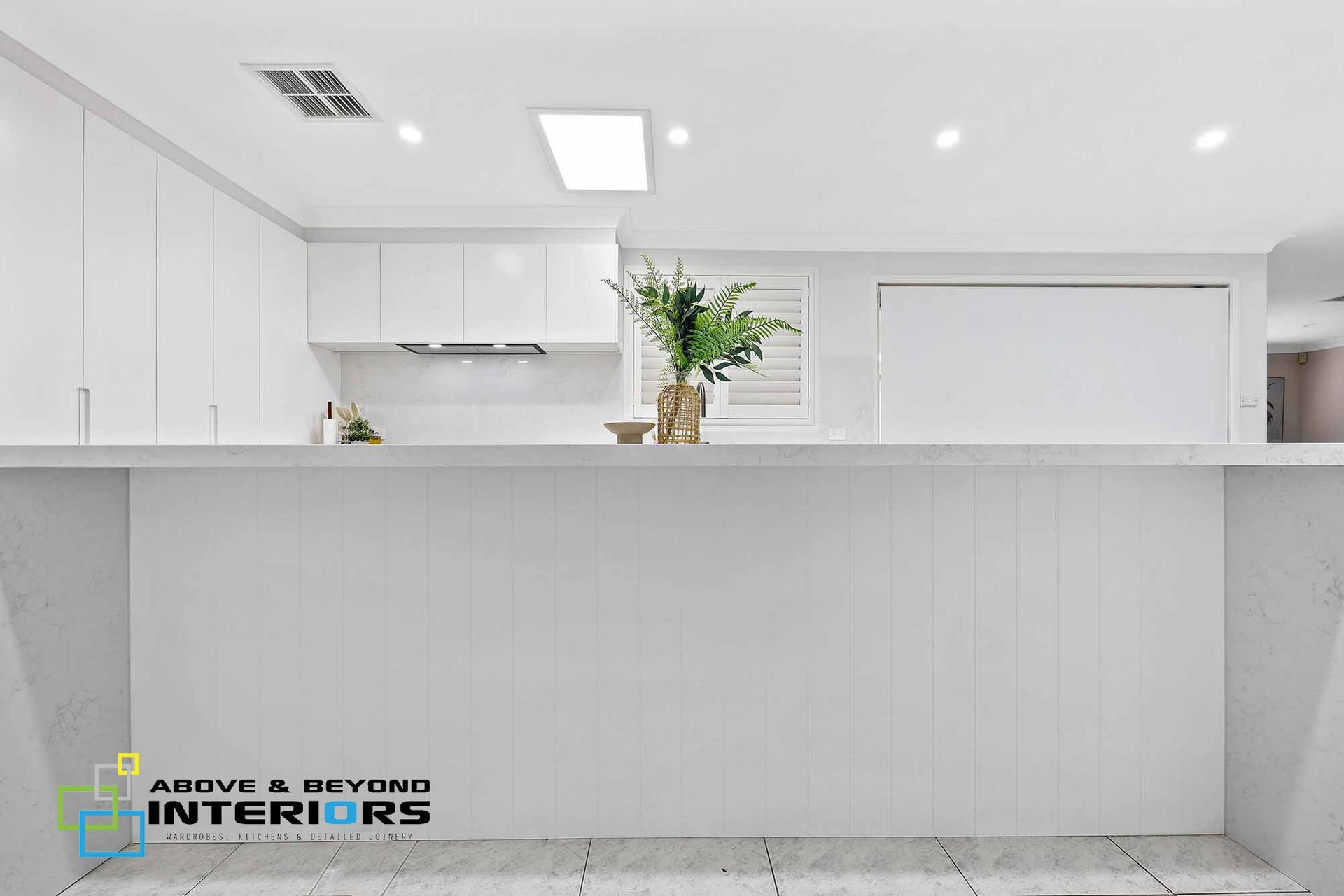 Bright White Modern Kitchen with Island, and Stainless Stove — Above & Beyond Interiors in Smeaton Grange, NSW
