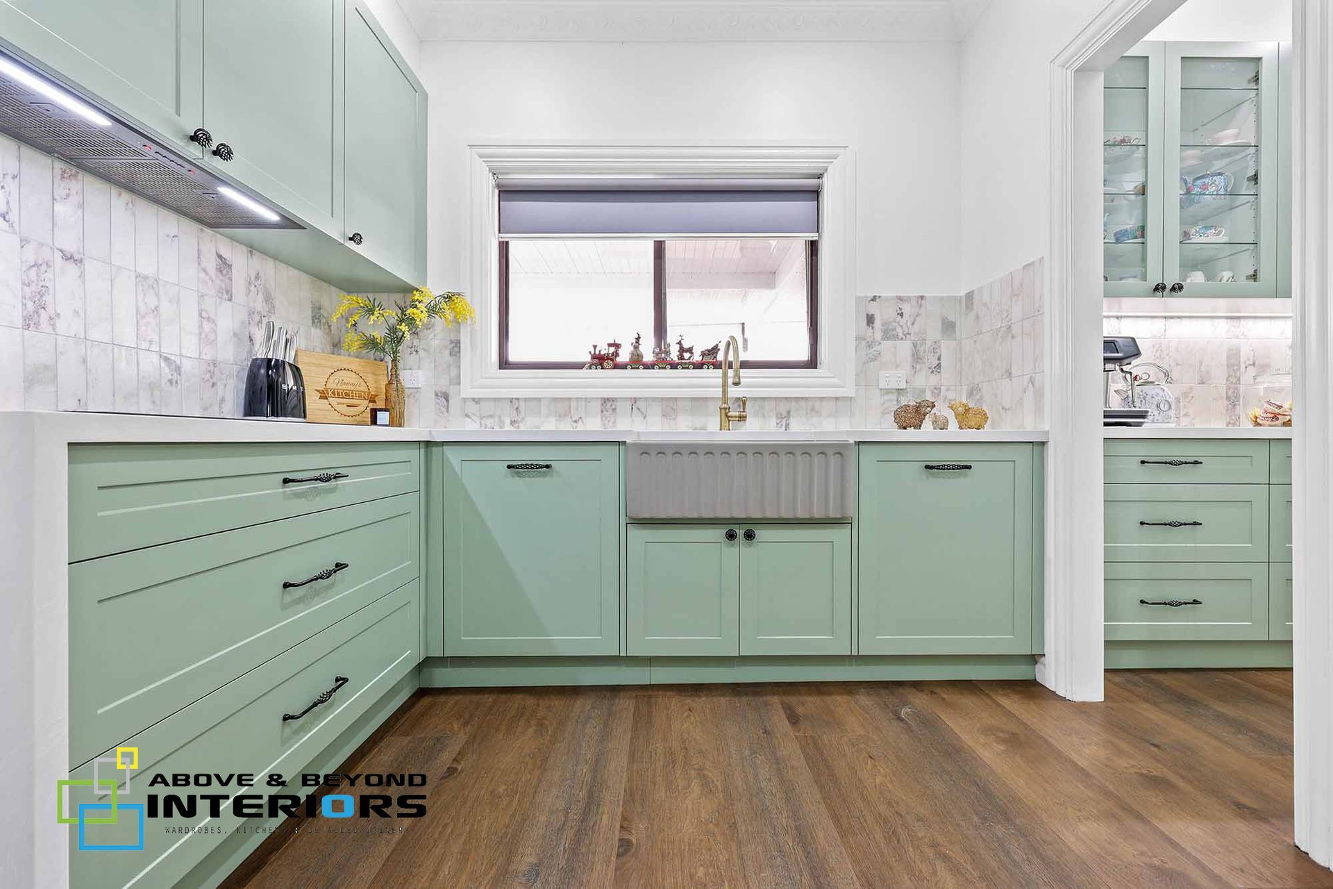 A Kitchen with Mint-Green Cabinets, White Marble Backsplash, and Wood Flooring — Above & Beyond Interiors in Smeaton Grange, NSW