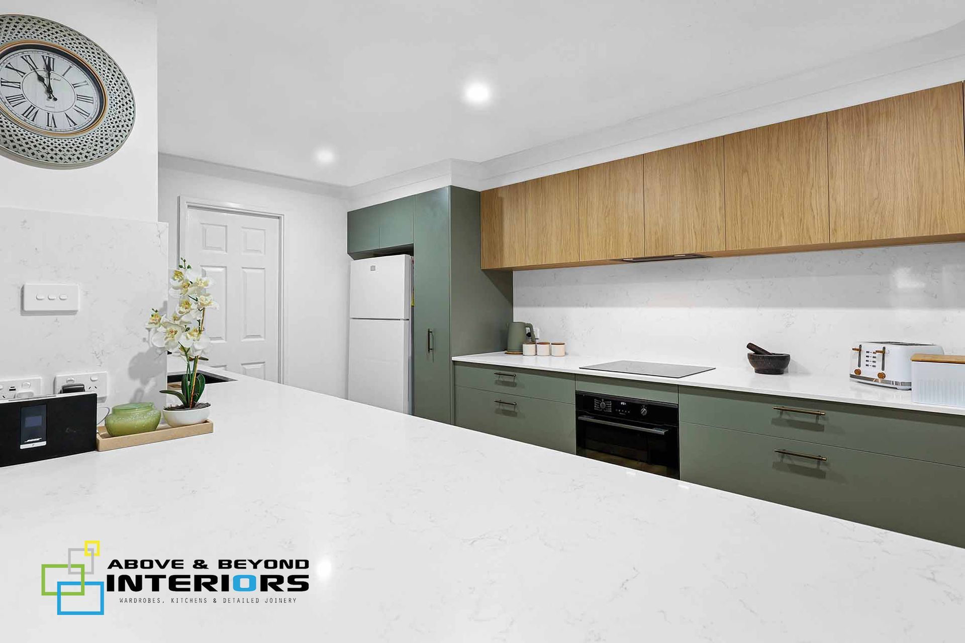 A Modern White Wood Upper Cabinets, and A Large Island Counter — Above & Beyond Interiors in Smeaton Grange, NSW