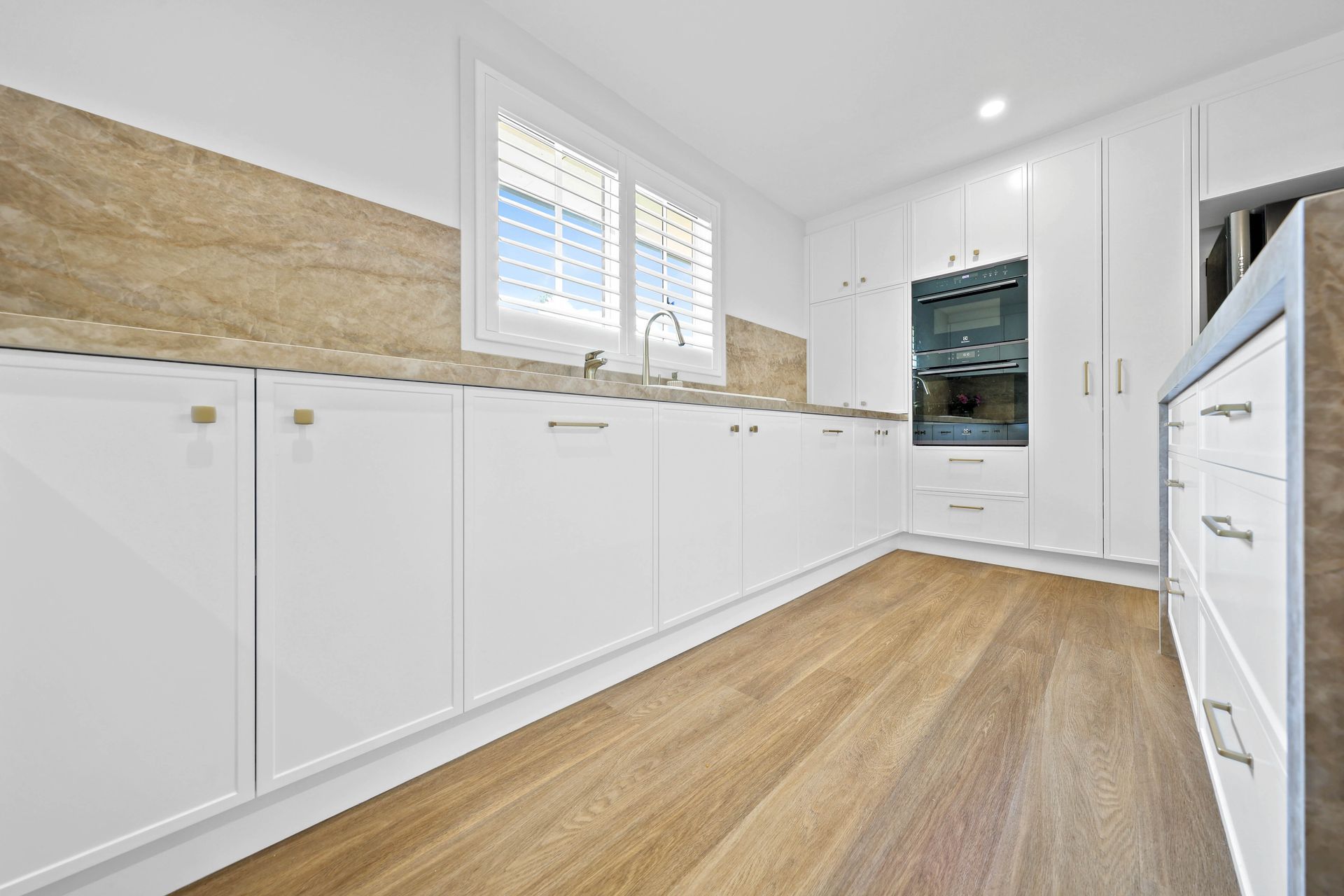 Bright White Kitchen With Wood Floors, Long Cabinets — Above & Beyond Interiors in Smeaton Grange, NSW