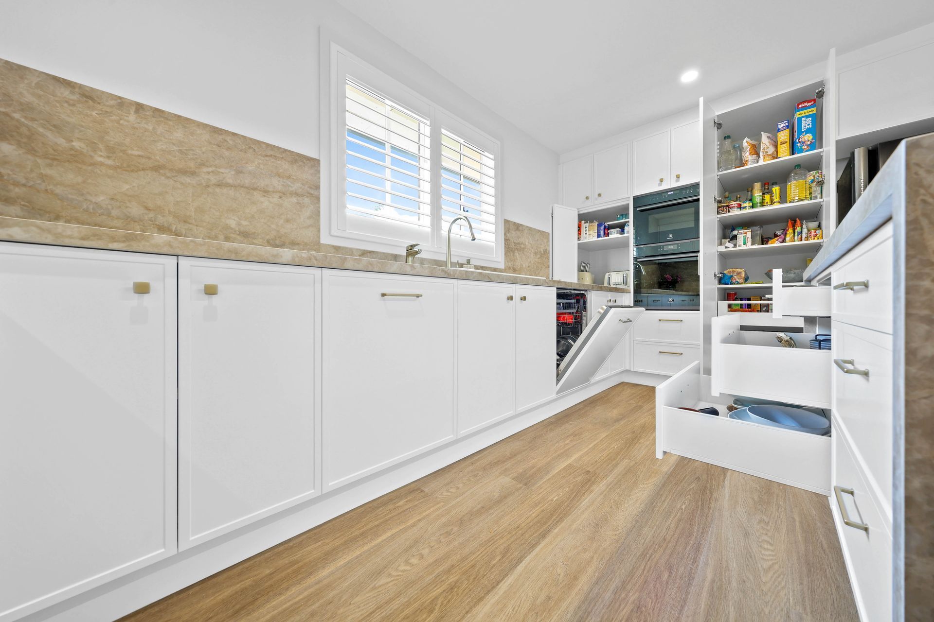 Bright White Kitchen With Wood Flooring — Above & Beyond Interiors in Smeaton Grange, NSW