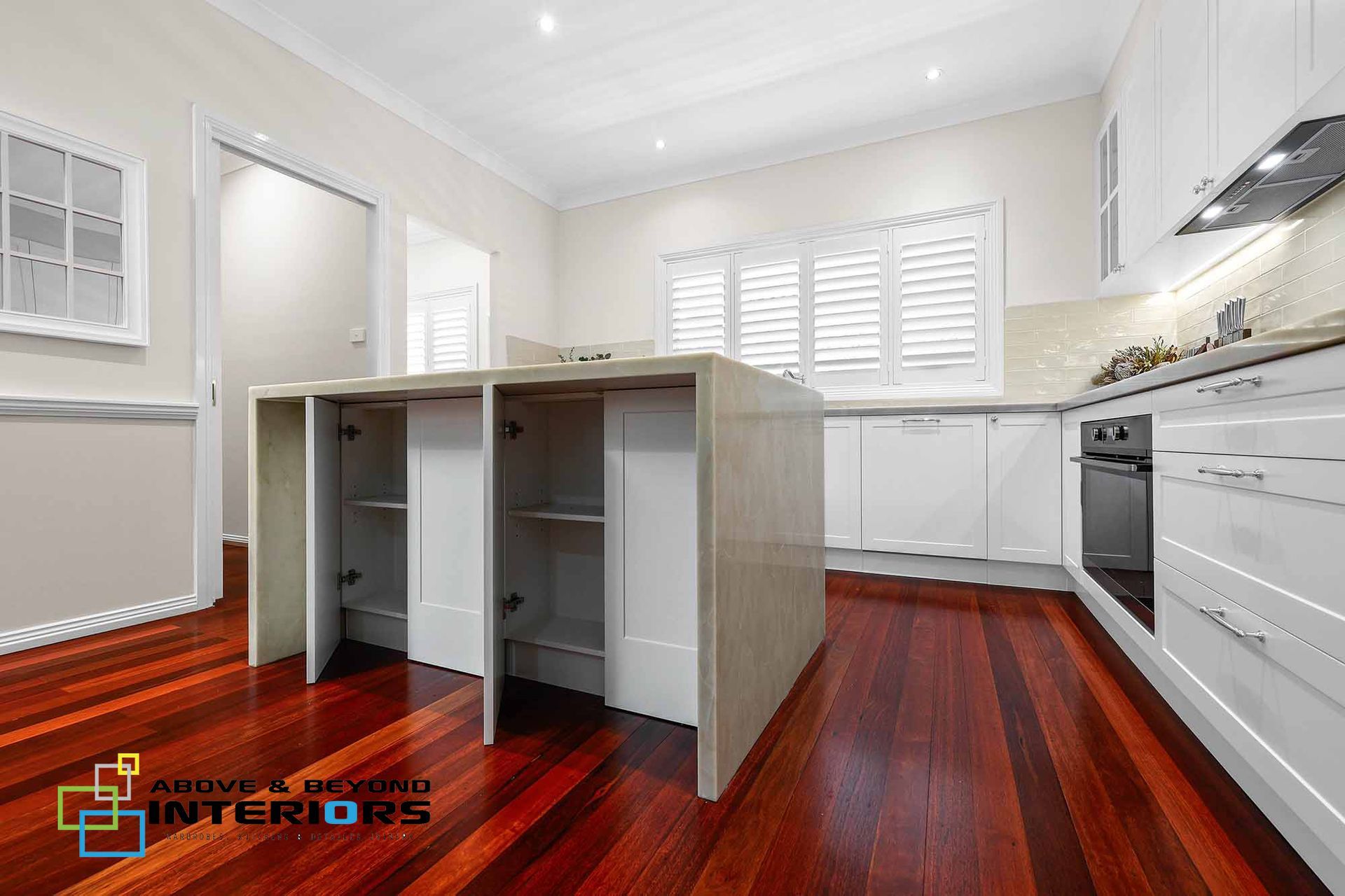 A Kitchen with White Cabinets, Wood Floors, and A Central Island — Above & Beyond Interiors in Smeaton Grange, NSW