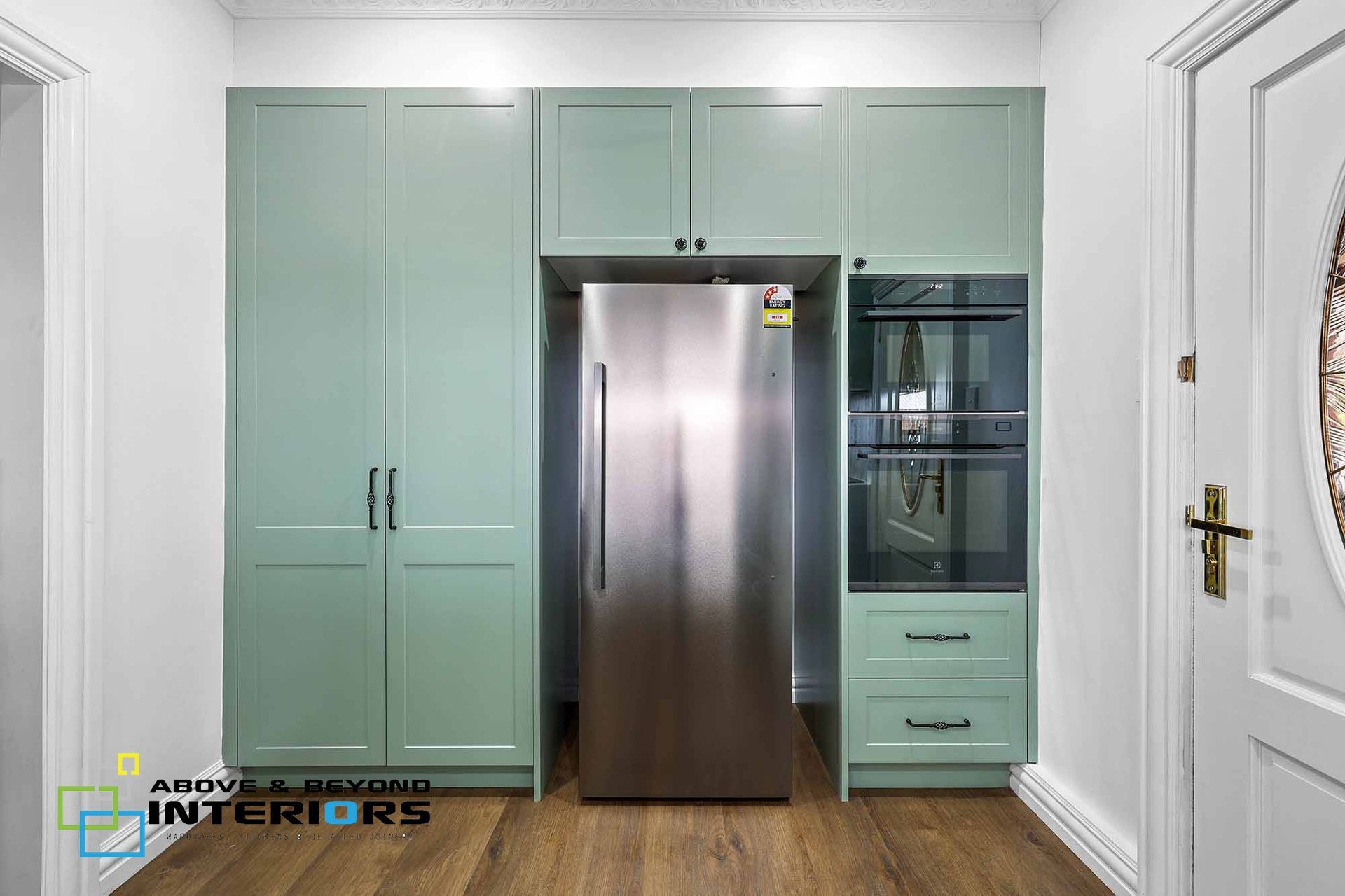 A Kitchen Cabinets with Stainless Steel Refrigerator and Wood Floor — Above & Beyond Interiors in Smeaton Grange, NSW