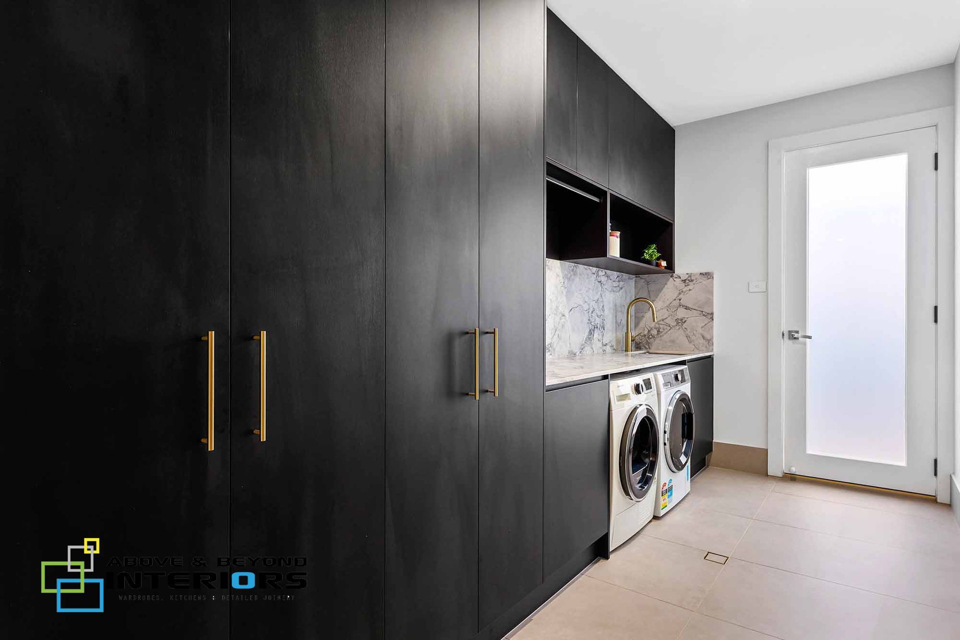 Modern Laundry Room with Dark Cabinets, Sink, and Frosted Glass Door — Above & Beyond Interiors in Smeaton Grange, NSW