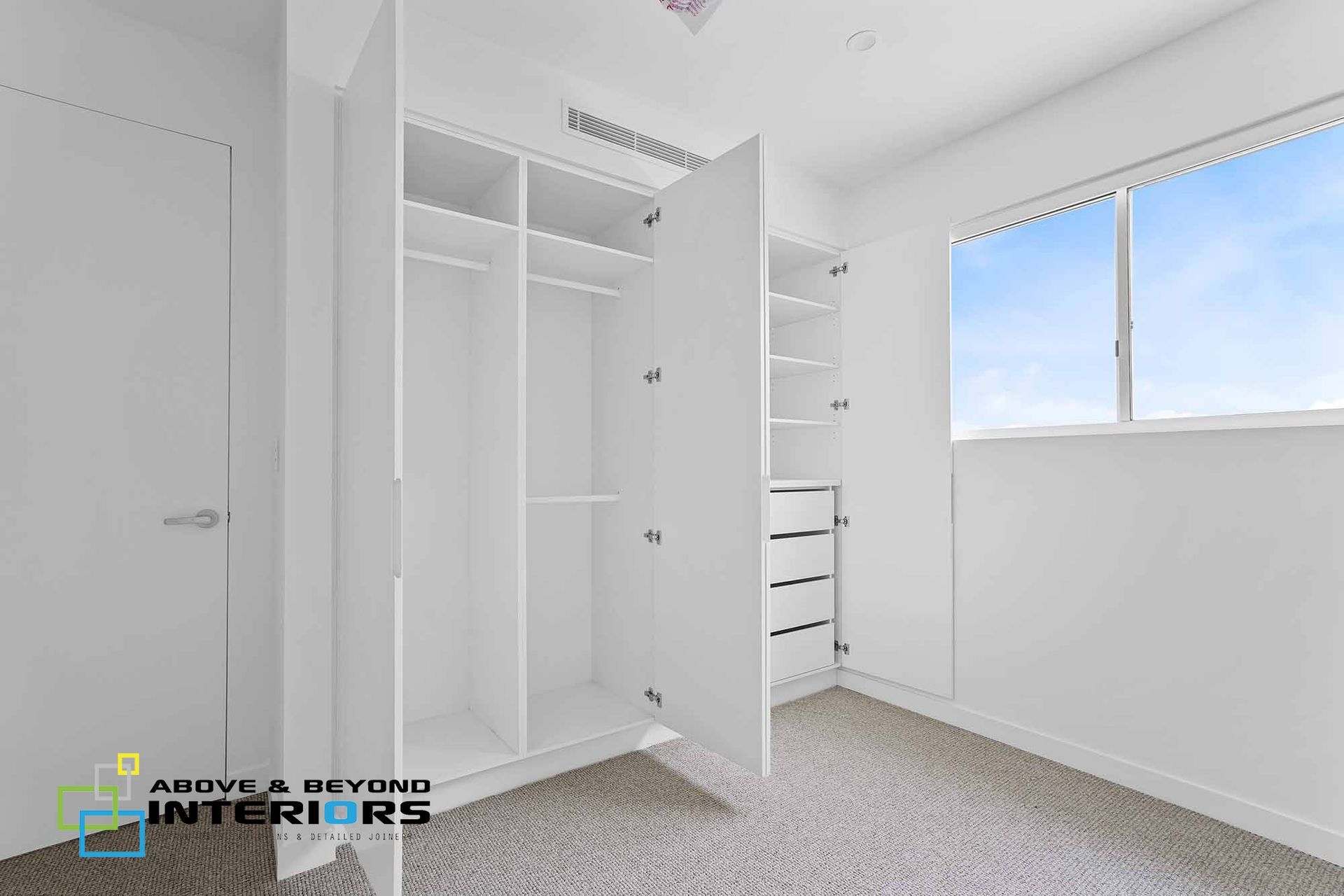 Bright White Bedroom with Open Closet Doors — Above & Beyond Interiors in Smeaton Grange, NSW