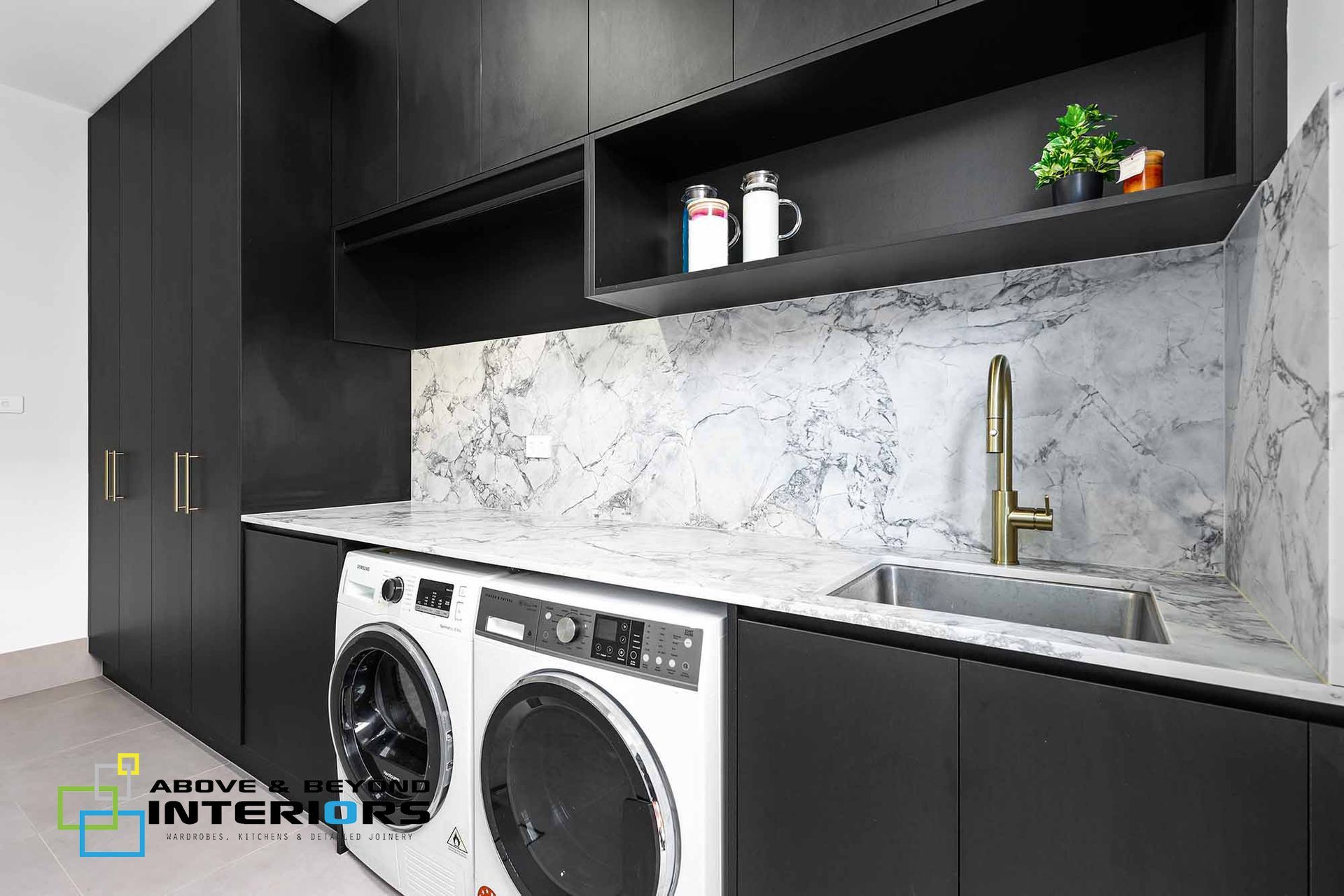 Modern Laundry Room with Black Cabinets, Marble Backsplash, and Stacked— Above & Beyond Interiors in Smeaton Grange, NSW