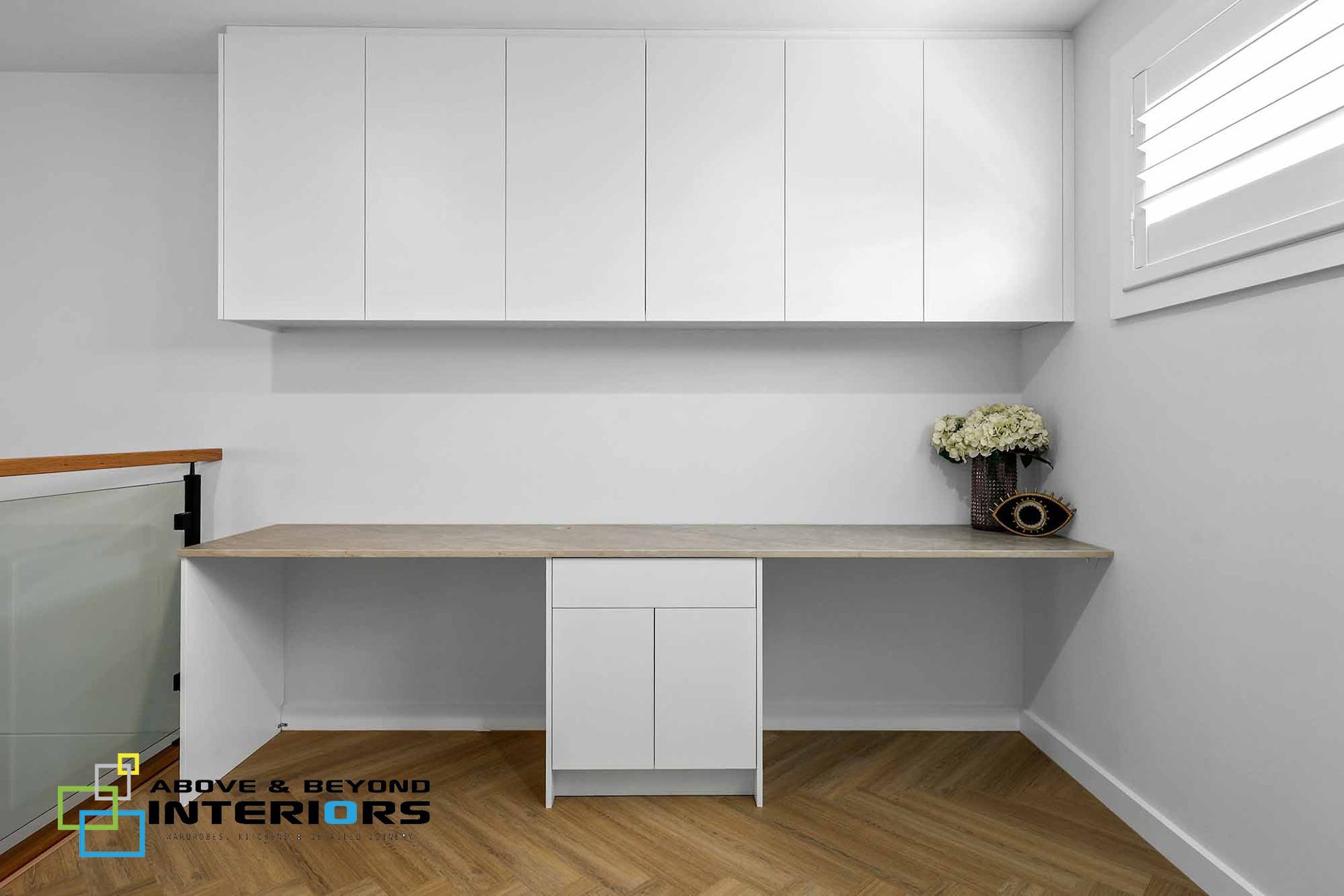 Minimalist Home Office with White Cabinets, Wood Desk, and Flowers by A Window — Above & Beyond Interiors in Smeaton Grange, NSW
