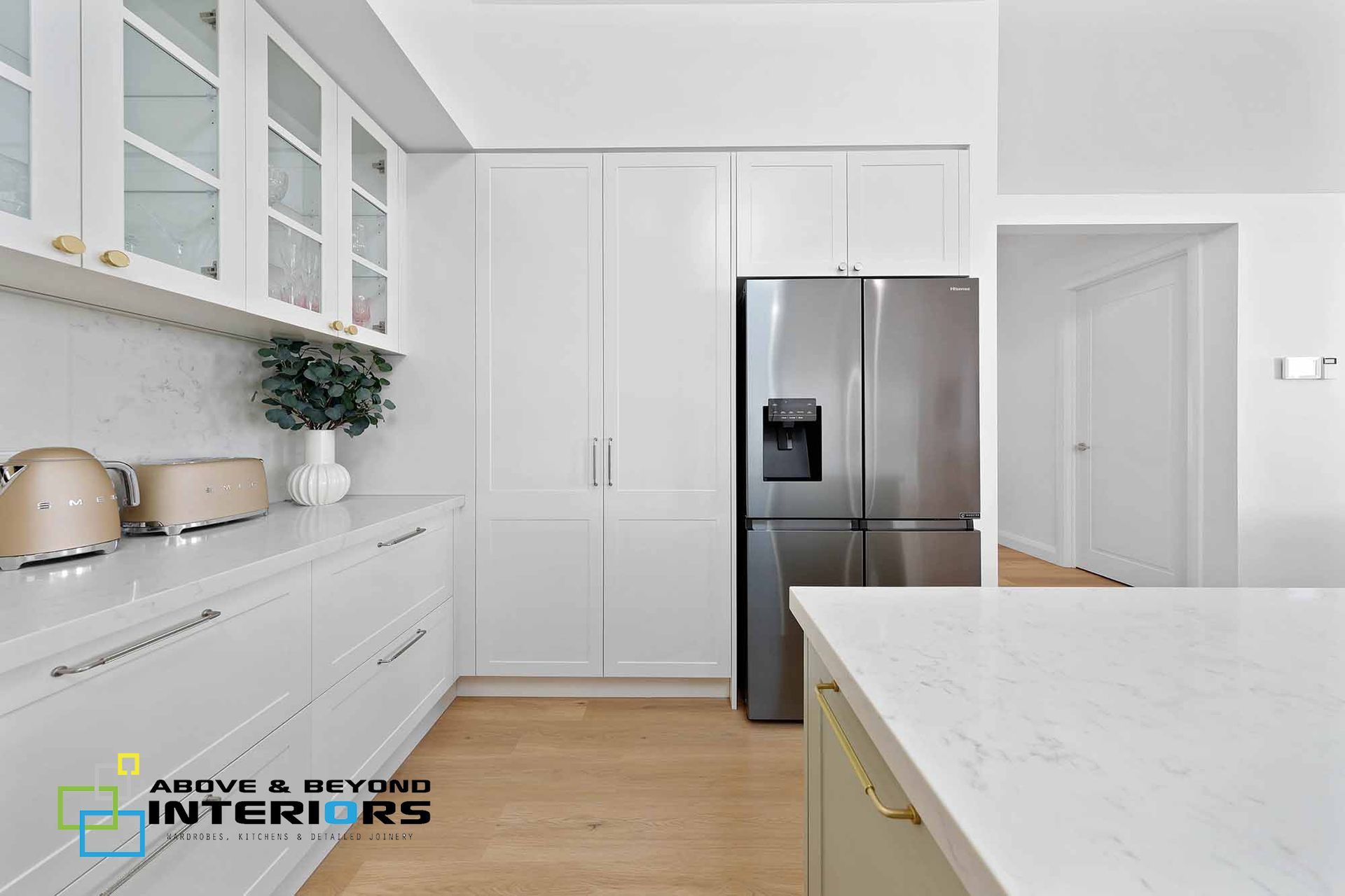 Bright Modern White Kitchen with Stainless Steel Fridge — Above & Beyond Interiors in Smeaton Grange, NSW