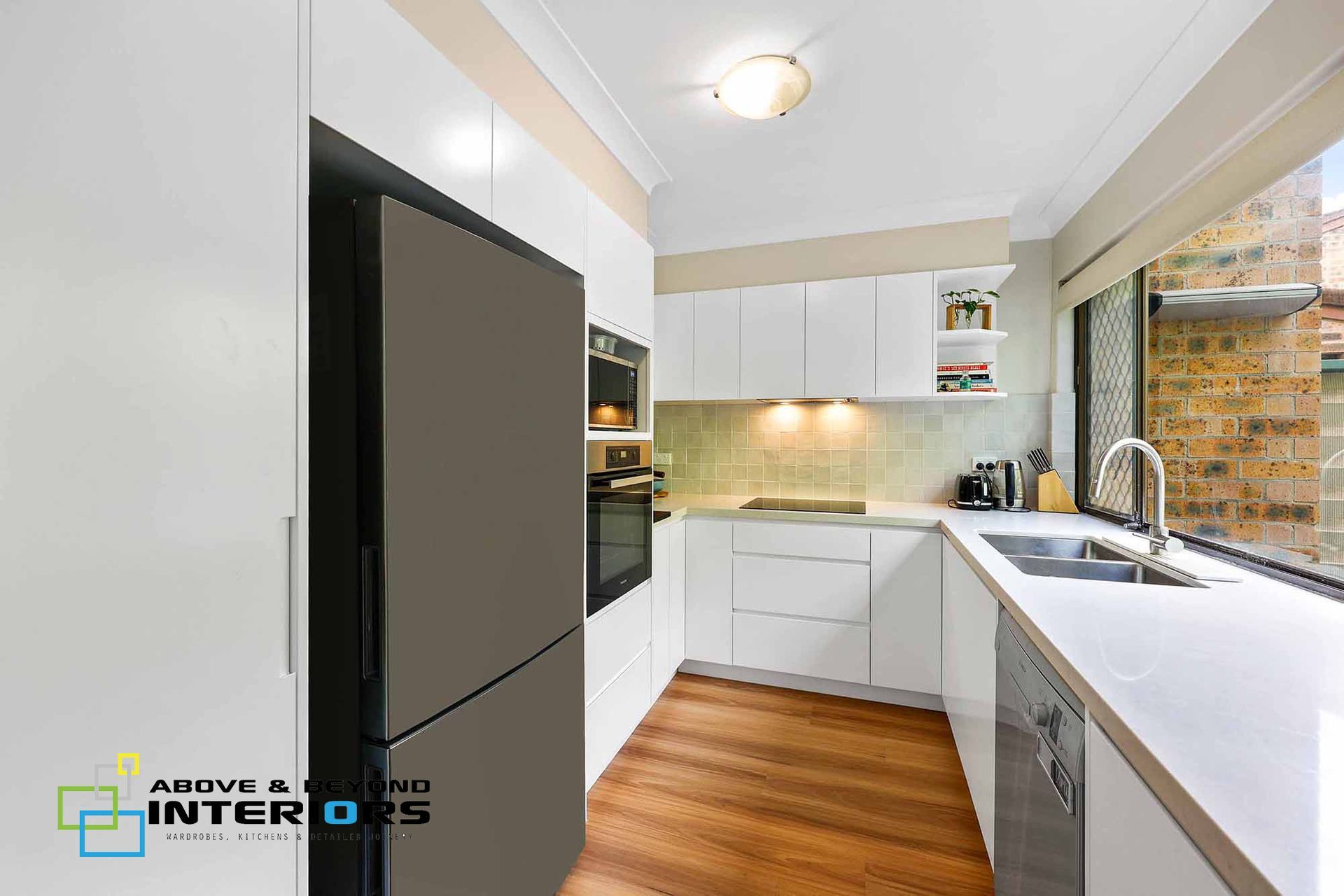Modern White Kitchen with Dark Built-In Fridge — Above & Beyond Interiors in Smeaton Grange, NSW