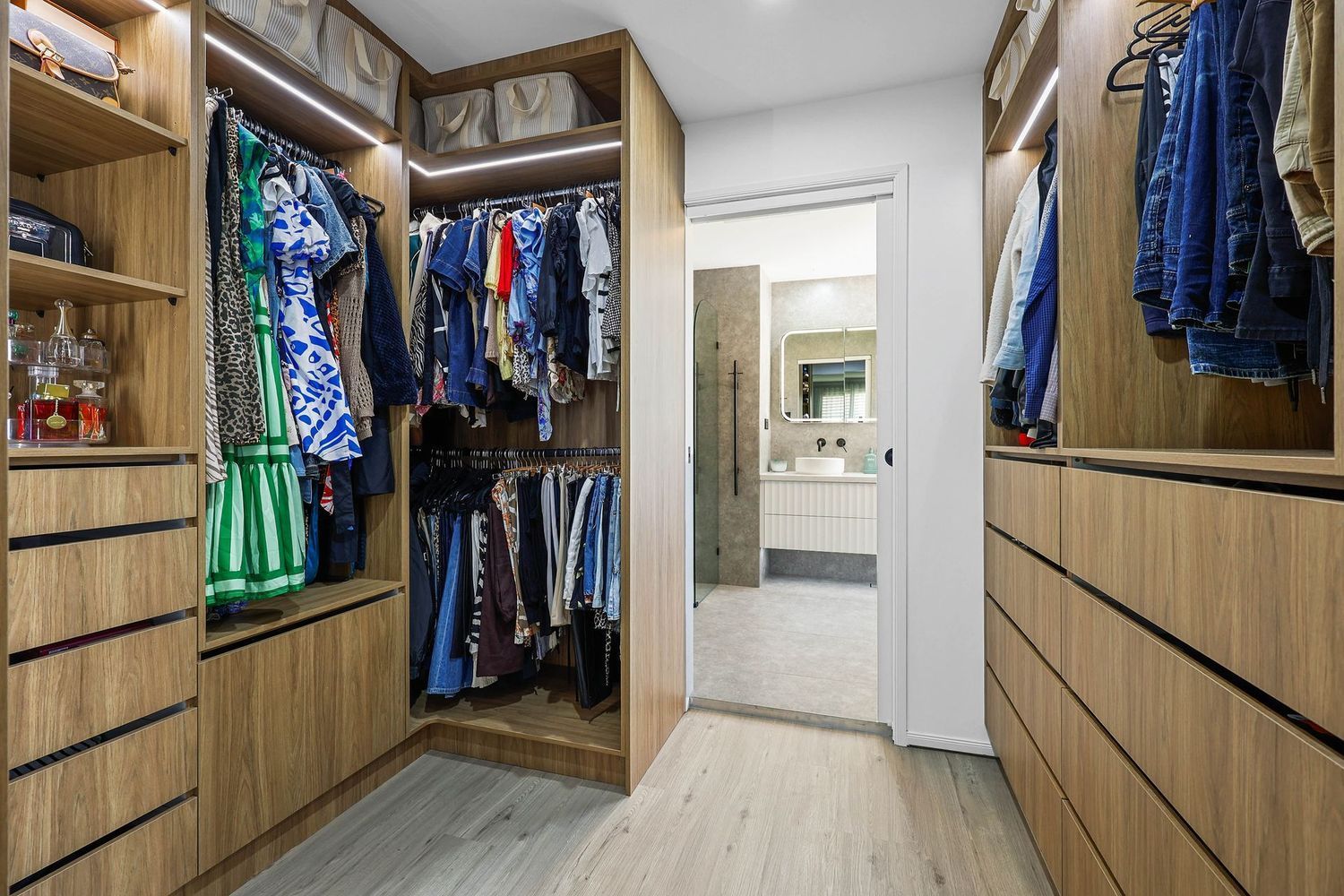 Spacious Walk-in Closet With Built-in Wood Cabinets, Hanging Clothes — Above & Beyond Interiors in Smeaton Grange, NSW