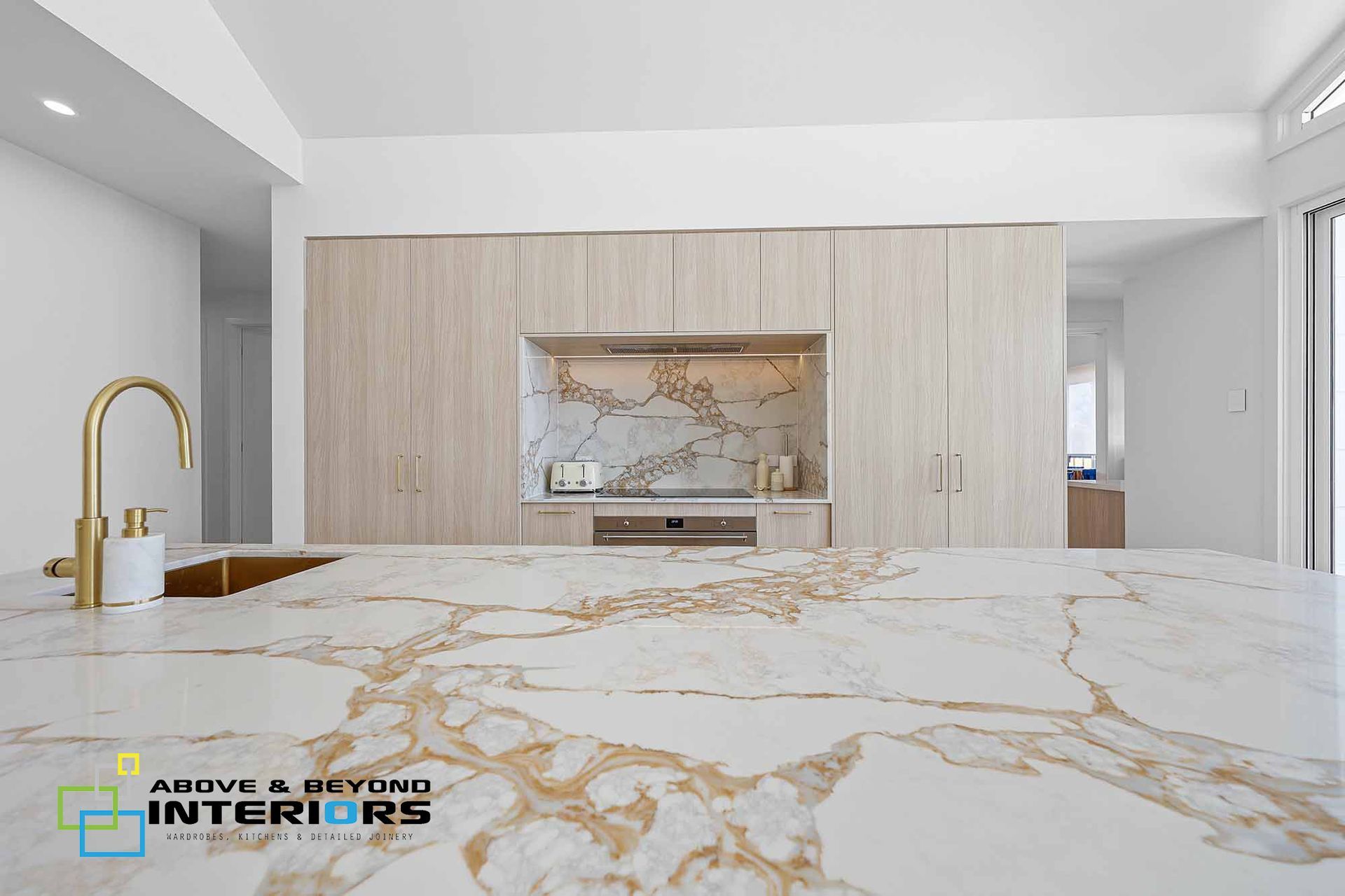 Modern White Kitchen with Gold Fixtures and Marble Countertops — Above & Beyond Interiors in Smeaton Grange, NSW