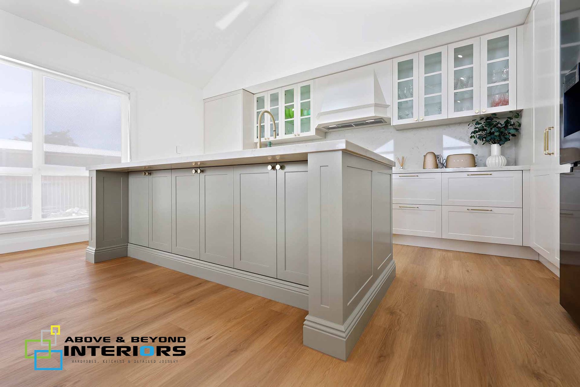 Bright White Kitchen with Gray Island, Wood Floors, and Large Windows — Above & Beyond Interiors in Smeaton Grange, NSW