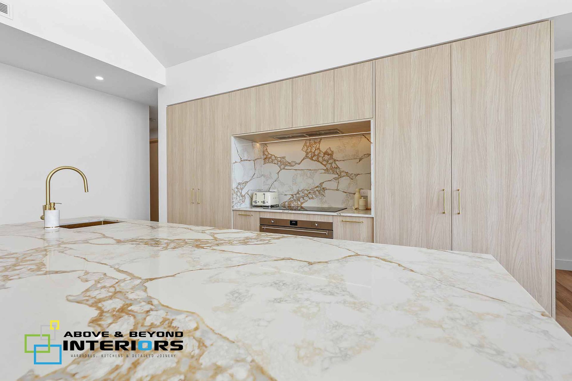 Modern White Kitchen with Marble Island and Gold Faucet — Above & Beyond Interiors in Smeaton Grange, NSW
