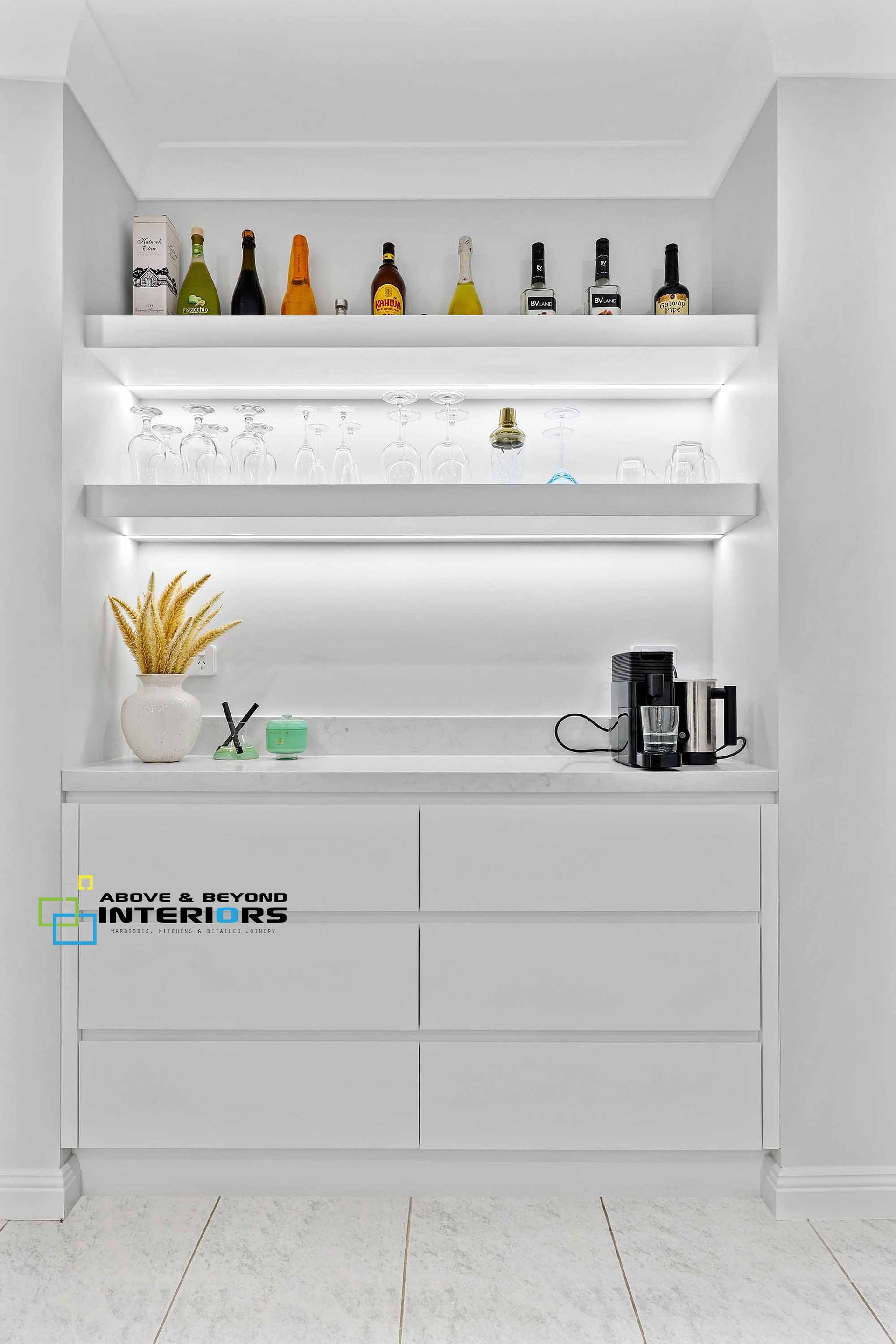 White Bar Cabinet with Shelves, Bottles, Glassware, and A Coffee Maker — Above & Beyond Interiors in Smeaton Grange, NSW