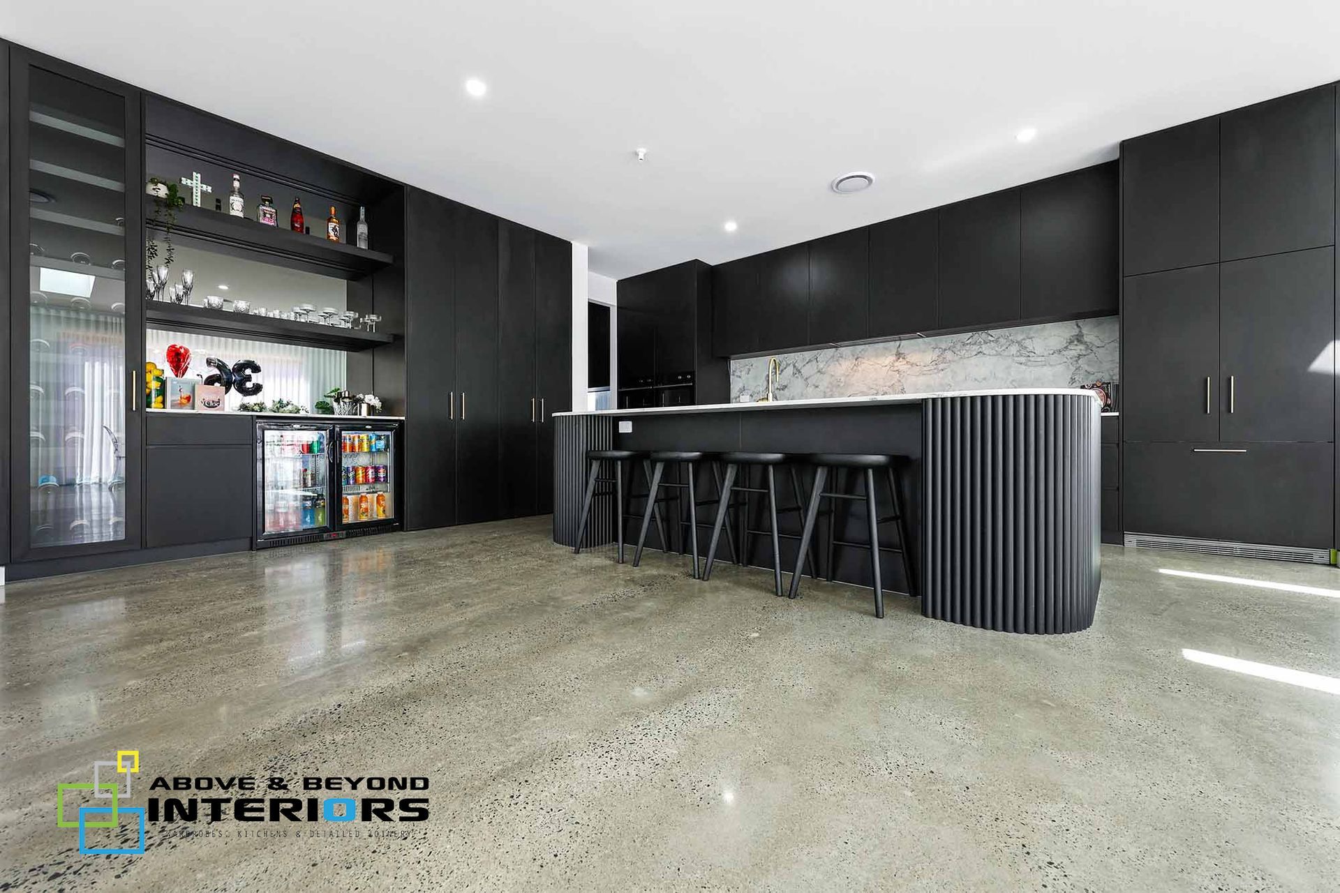 Modern Black Kitchen with Bar Stools, Stone Floor, and Built-In Shelving — Above & Beyond Interiors in Smeaton Grange, NSW
