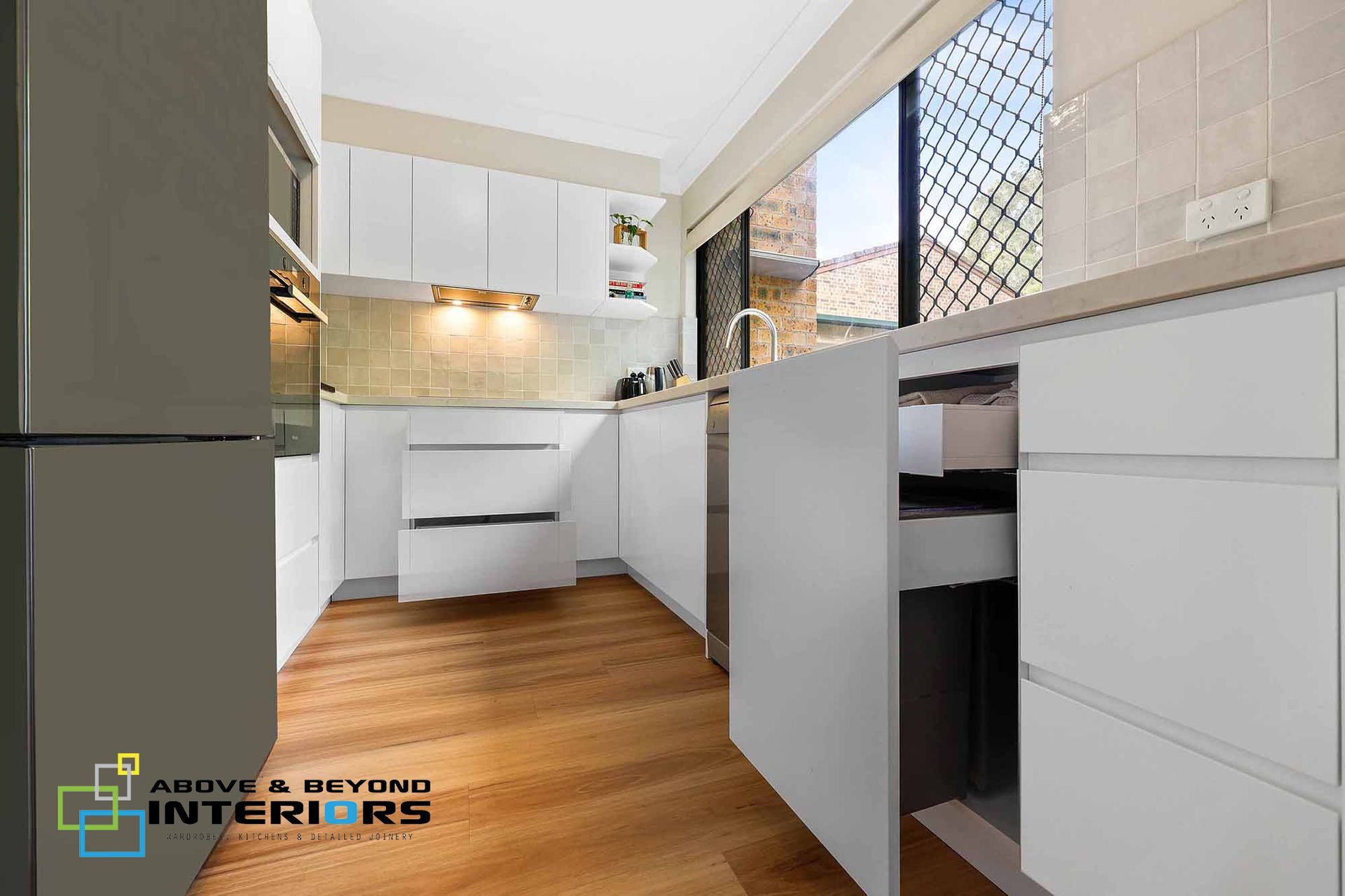 Modern White Kitchen with Wood Floor — Above & Beyond Interiors in Smeaton Grange, NSW