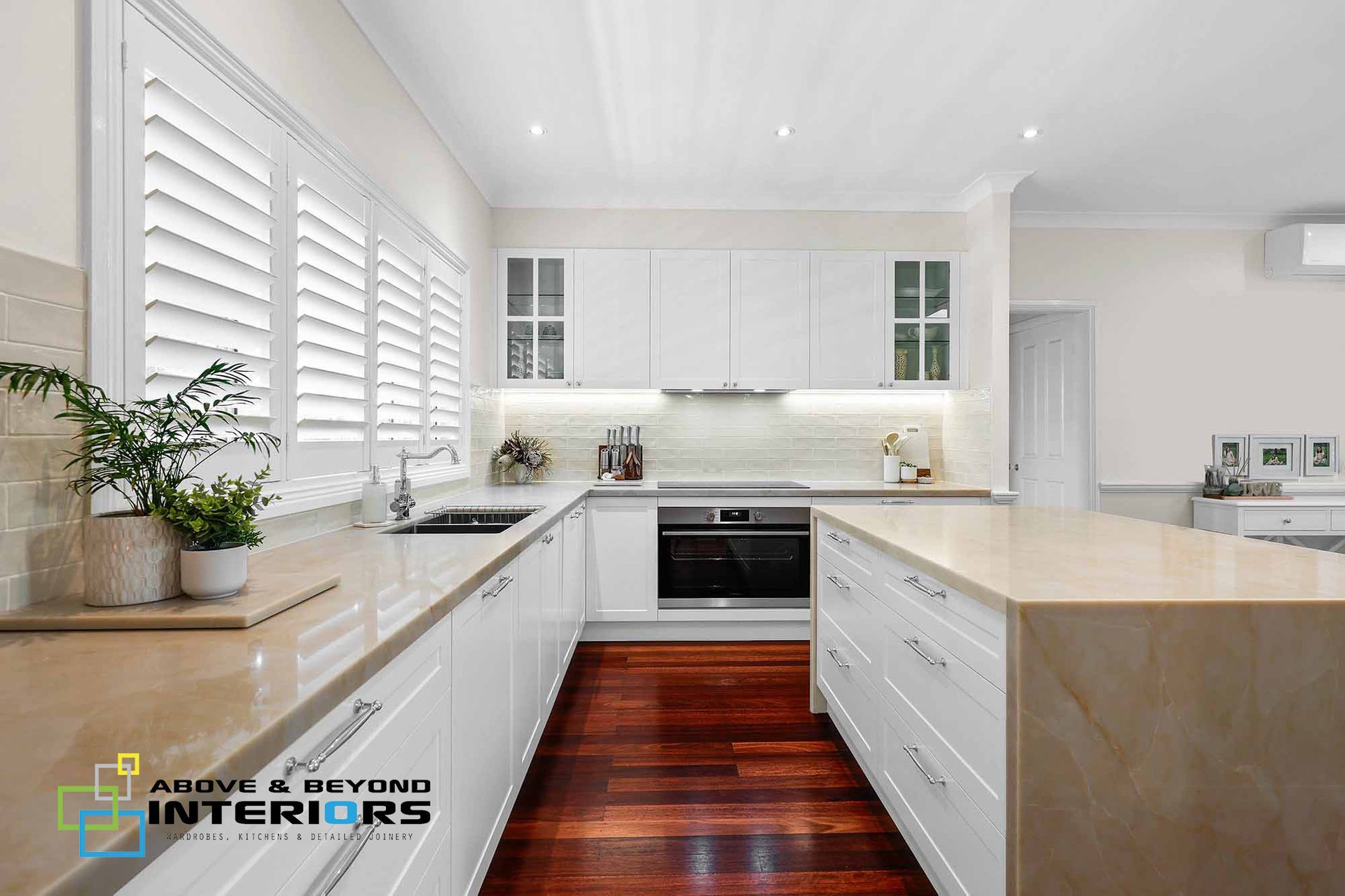 Bright Modern White Kitchen with Dark Wood Floor, and Large Windows — Above & Beyond Interiors in Smeaton Grange, NSW