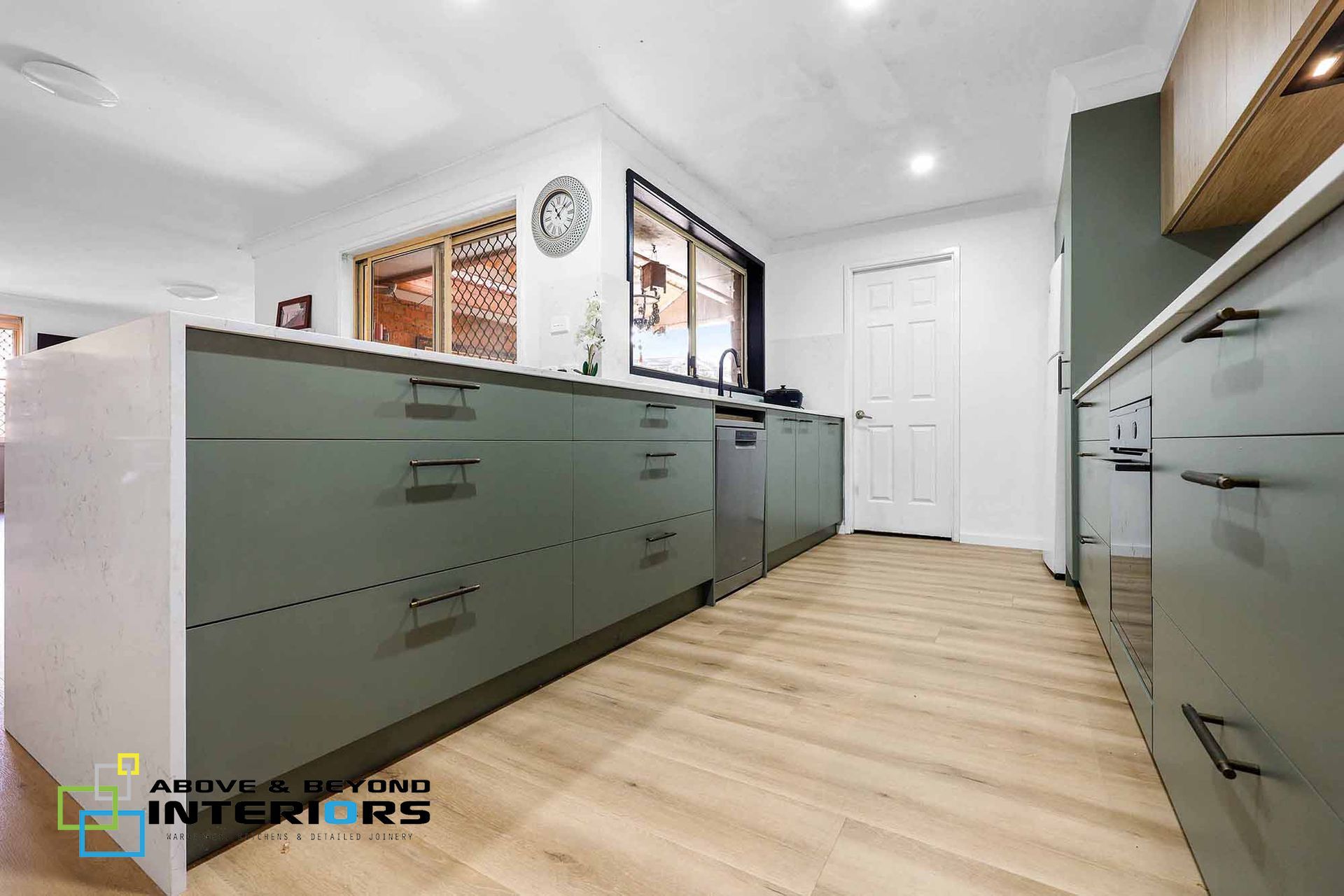 Bright Modern Galley Kitchen with Sage Cabinets — Above & Beyond Interiors in Smeaton Grange, NSW