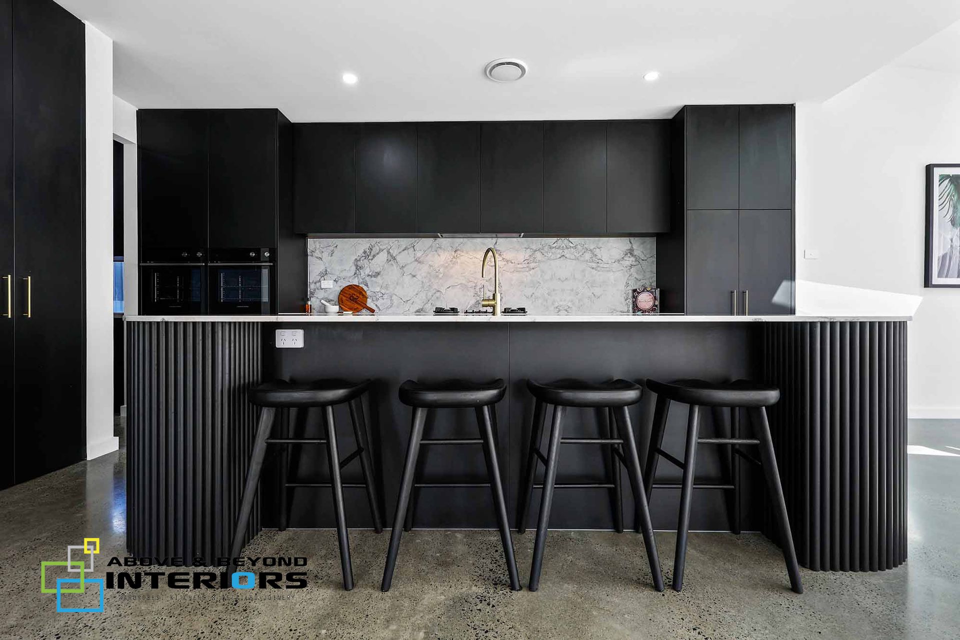 Modern Kitchen with Four Black Bar Stools at A Breakfast Counter — Above & Beyond Interiors in Smeaton Grange, NSW