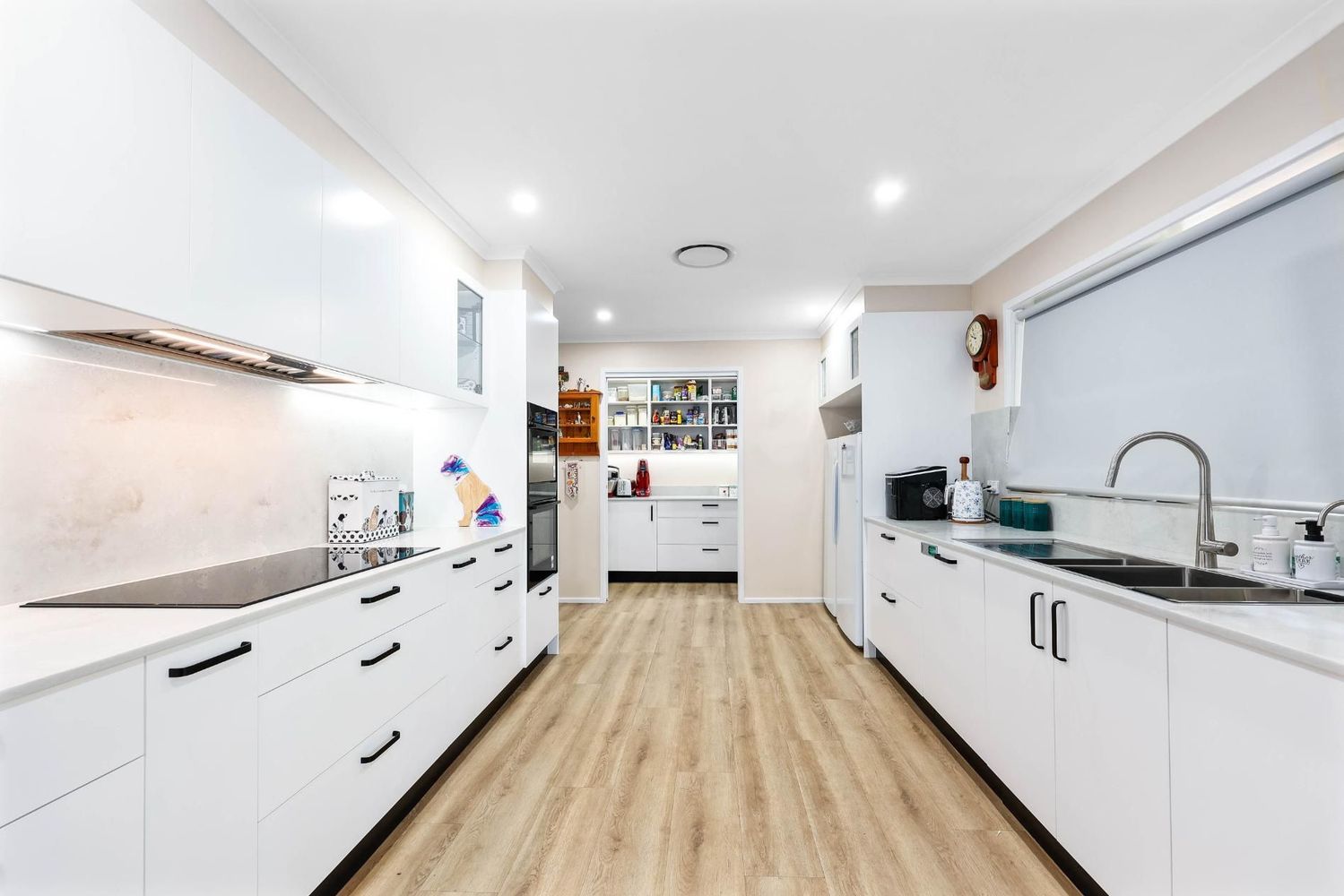 Bright Modern White Kitchen With Wood Flooring — Above & Beyond Interiors in Smeaton Grange, NSW