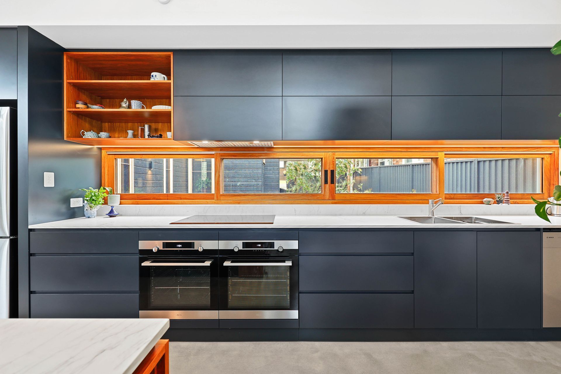 Modern Kitchen With Dark Cabinets, Wood Accent Shelves — Above & Beyond Interiors in Smeaton Grange, NSW