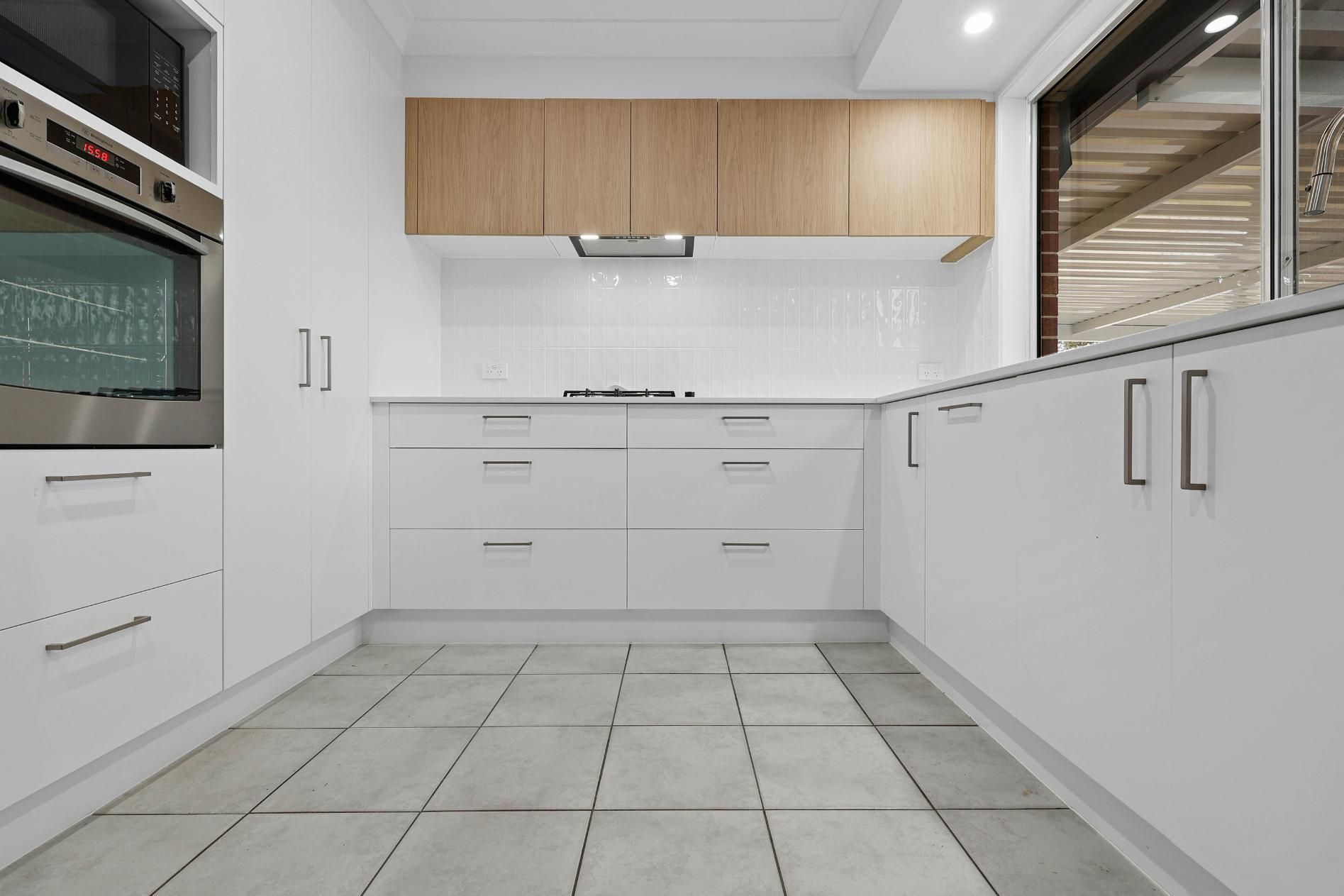 Bright Modern White Kitchen With Wood Cabinets — Above & Beyond Interiors in Smeaton Grange, NSW