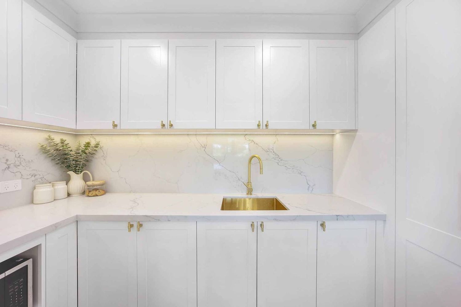Bright White Minimalist Kitchen With Gold Faucet — Above & Beyond Interiors in Smeaton Grange, NSW