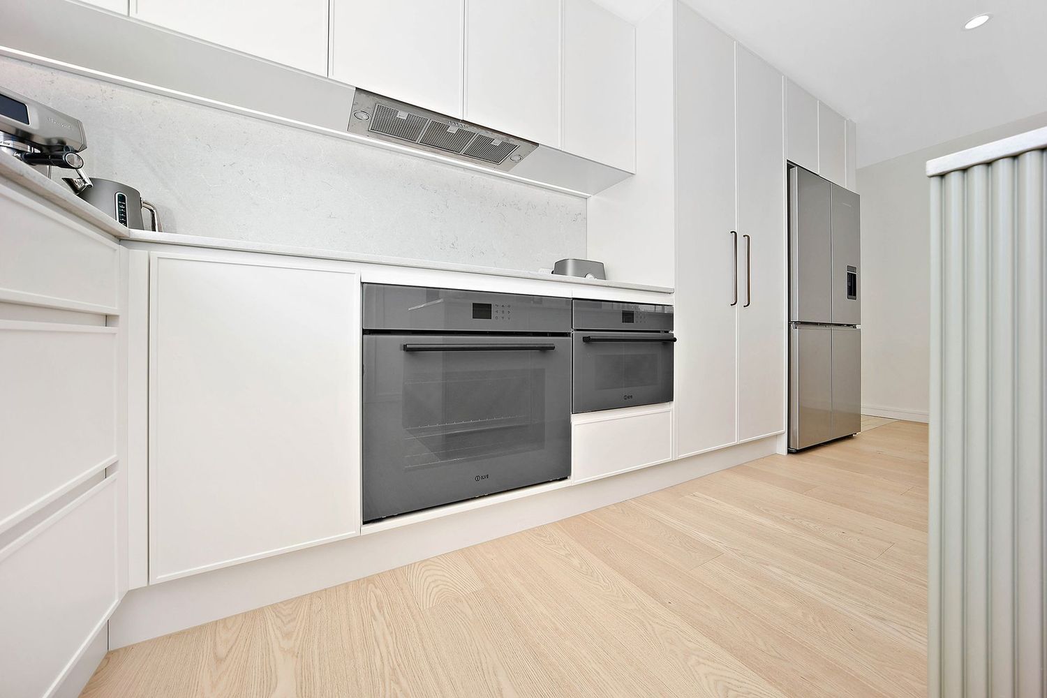 Bright Modern White Kitchen With Built-in Oven — Above & Beyond Interiors in Smeaton Grange, NSW