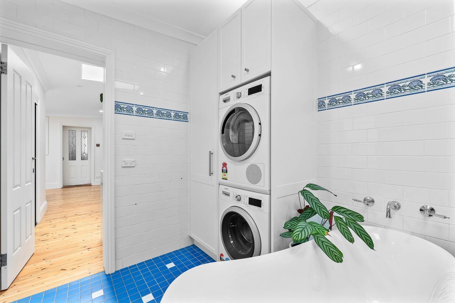 Bright Laundry Room and Bathroom With Stacked Washer-dryer — Above & Beyond Interiors in Smeaton Grange, NSW